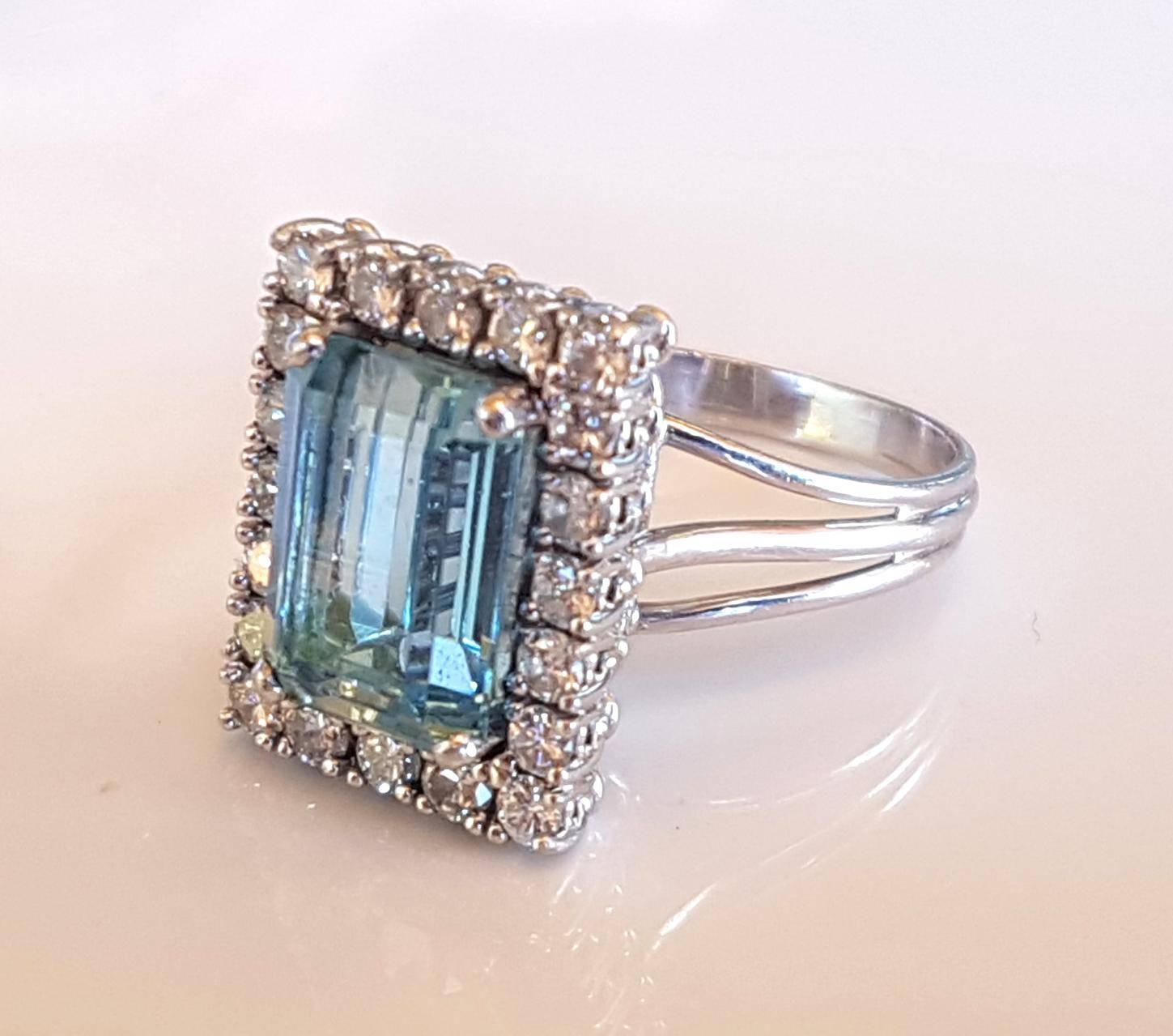 Big and bold, this 18ct white gold aquamarine and diamond dress ring is platinum set with a medium light blue emerald cut aqua of 3.35ct surrounded by 20 round brilliant cut diamonds of total weight 0.95ct G-H VS-SI.  Wire basket underrail and