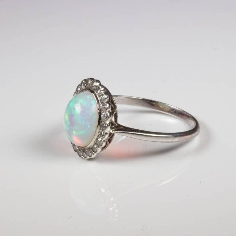 Gorgeous oval opal and diamond cluster ring is set with 22 single cut diamonds of 0.01ct each and an oval cabachon cut opal showing green, blue and orange colours. All platinum. Currently size L (US = 5 3/4) and will be safely sized by our expert