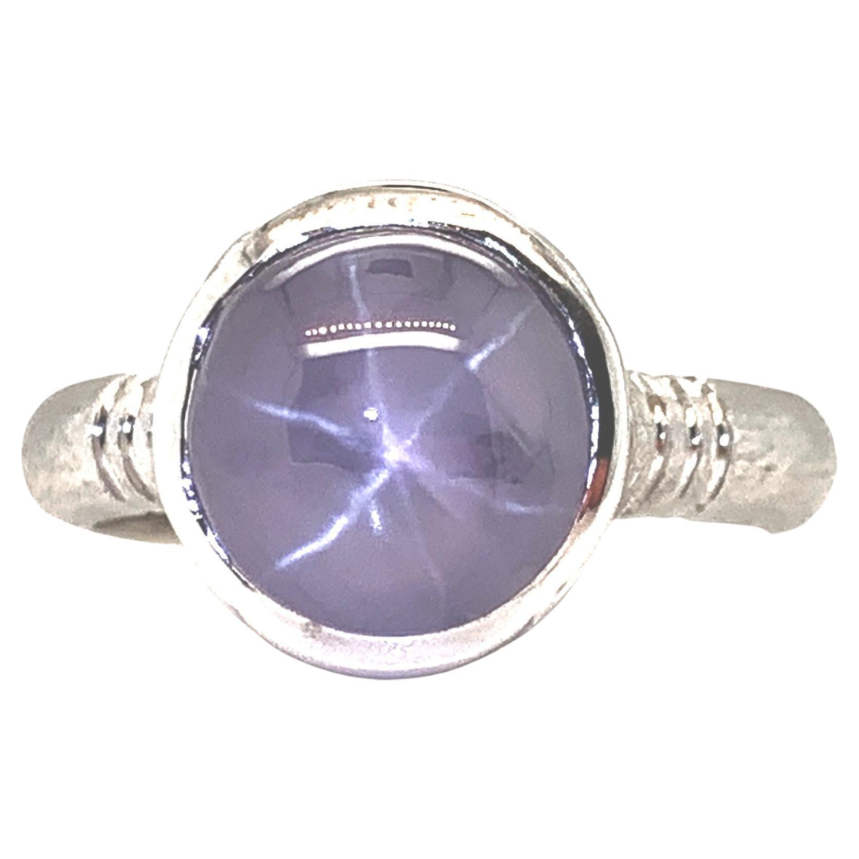 This eye-catching ring features a large, 6.36 carat oval silvery blue star sapphire cabochon set in an 18k white gold bezel. One of the most highly-prized phenomenal gemstones, this sapphire displays a 6-rayed star when viewed from a concentrated