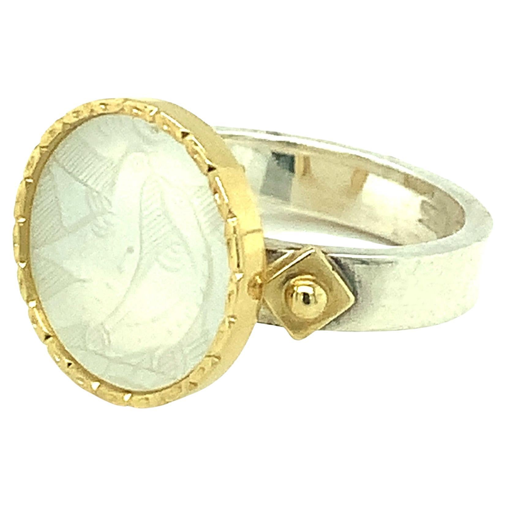 This ring features an antique, mother-of-pearl Chinese gambling counter with motifs dating back to the 18th century. The counter was originally carved in China for export to Britain. The British used these mother of pearl pieces much like we would