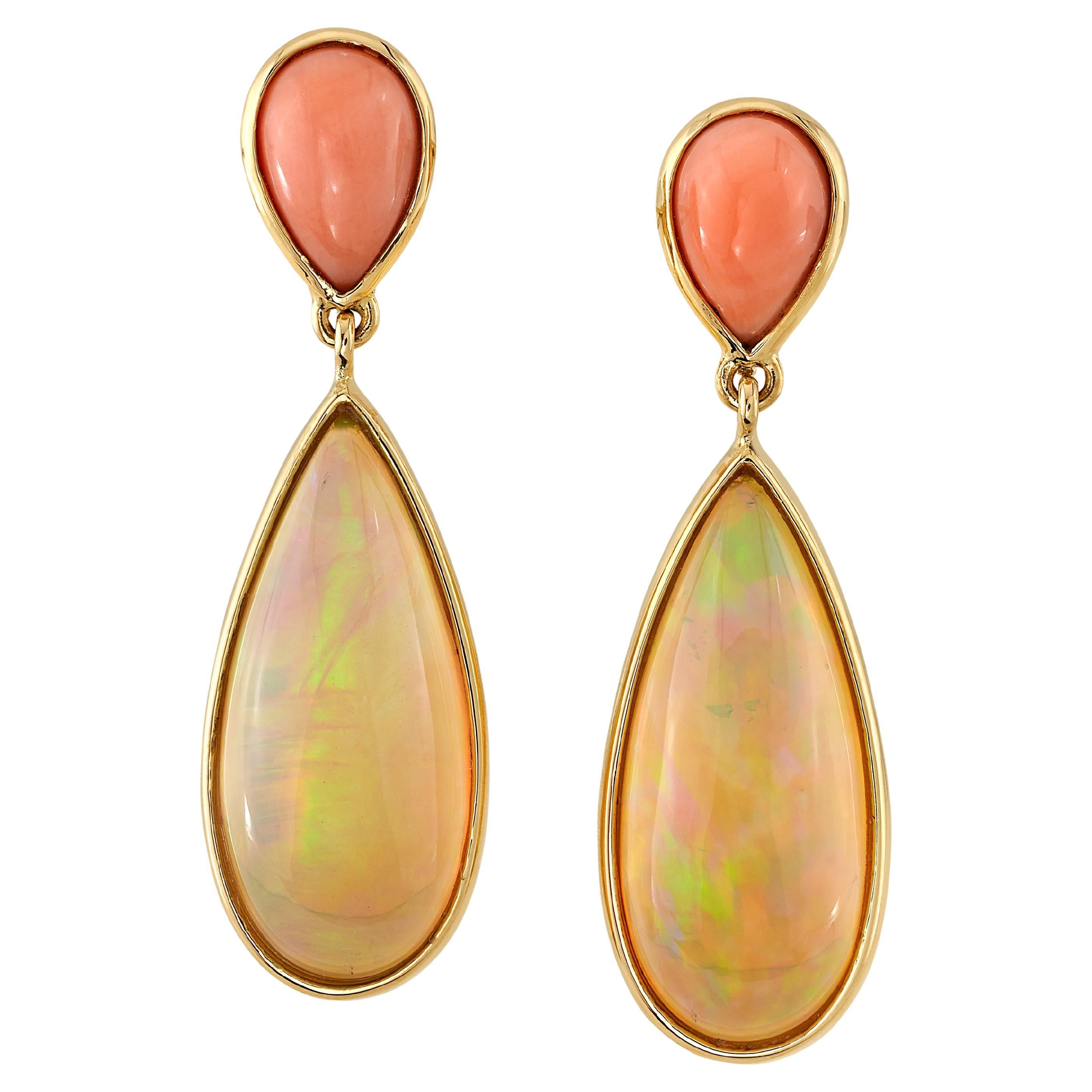 These gorgeous dangle earrings feature colorful pear-shaped Ethiopian opals dangling from lovely peach coral cabochons set in 18k yellow gold! The opals have striking play-of-color, with orange and bright green flashes that complement the peach