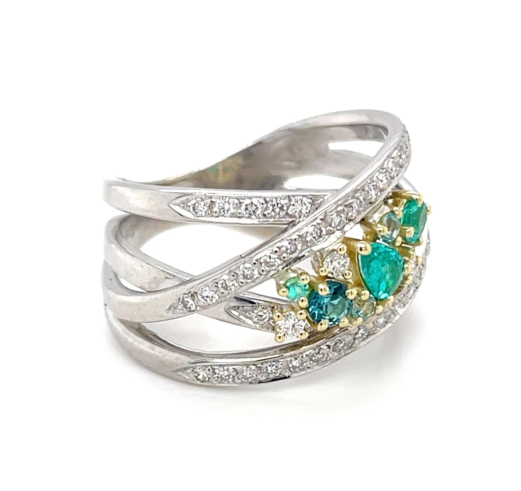 Cette bague accrocheuse présente une collection d'étonnantes tourmalines brésiliennes Paraiba et d'étincelants diamants blancs magnifiquement sertis dans un luxueux design enveloppant en or blanc et jaune 18 carats. Les tourmalines Paraiba de cette