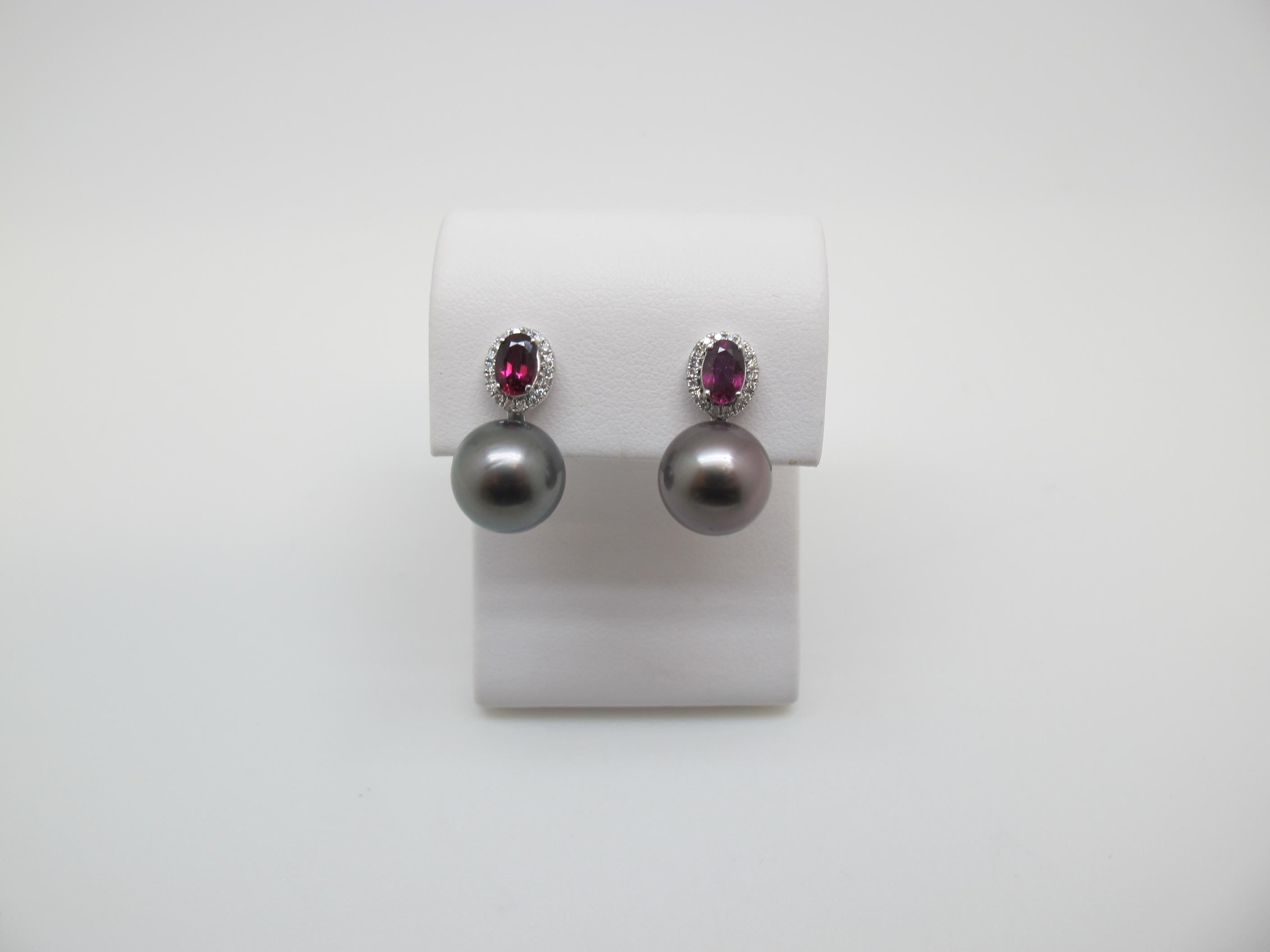 These impeccable pearl drop earrings display dramatic colors with elegant perfection! Featuring bright red rubies surrounded by a halo of diamonds and large, black Tahitian pearls, these are earrings to lust after! The rich color of the rubies