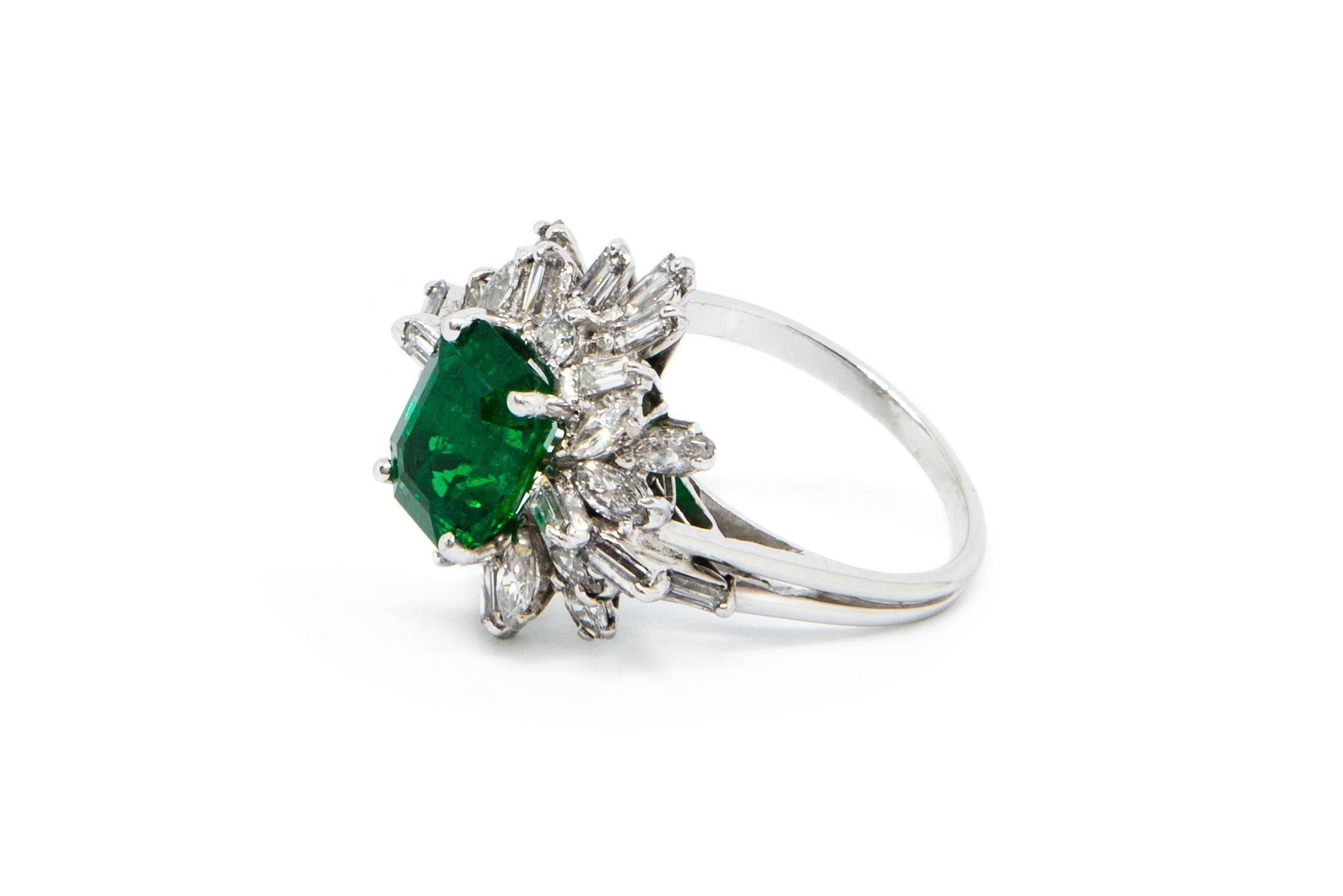 A certified Zambia Natural Emerald and diamond cluster ring set in 18ct white gold. (Emerald Report n. 13213)
 
Emerald measurement: 9.1 x 7.0 x 5.0mm
16 rectangular, step cut diamonds
12 marquise shaped diamonds
2 round brilliant cut diamonds

