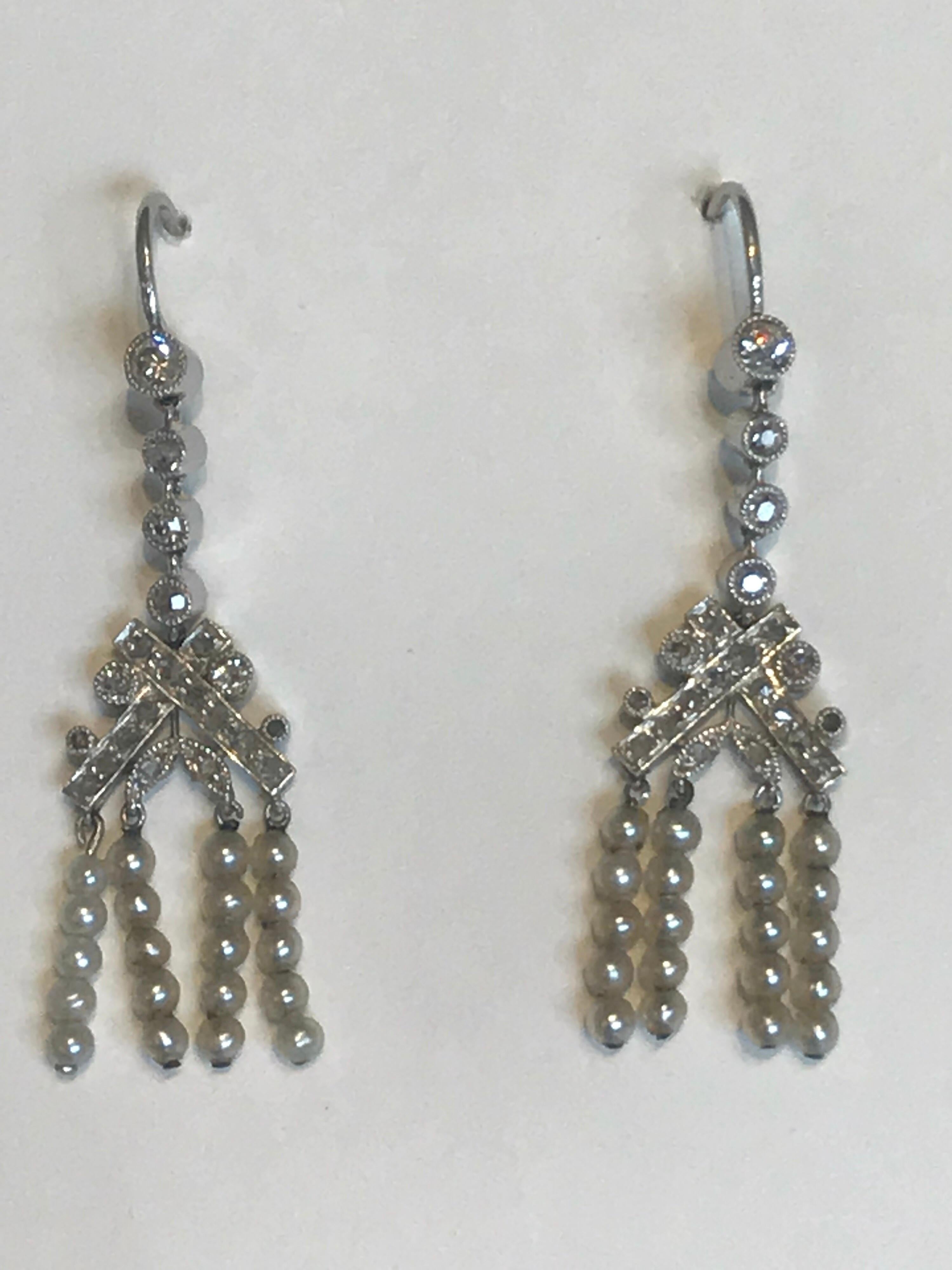 A pair of earrings dating from the Edwardian era, set with diamonds and pearl, flapper girl earrings, perfectly set in platinum with old cut diamonds throughout with a laurel emblem.  The pearls are articulated and move when the wearer moves.  The