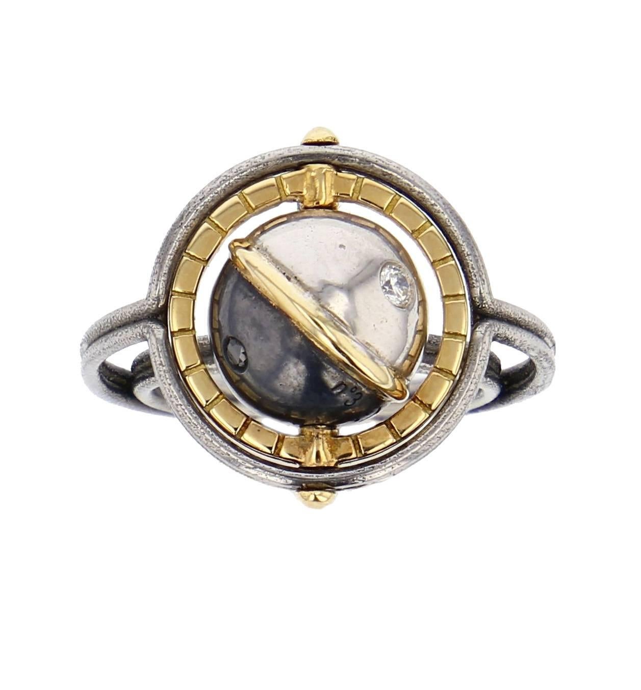 MIR Ring Gold Silver Diamonds

Gold ring made of 2 polished steel bands, carrying a white gold and patinated silver globe, circled in yellow gold. This moving planet is set with white and black diamonds, and a yellow gold satellite rotating around.