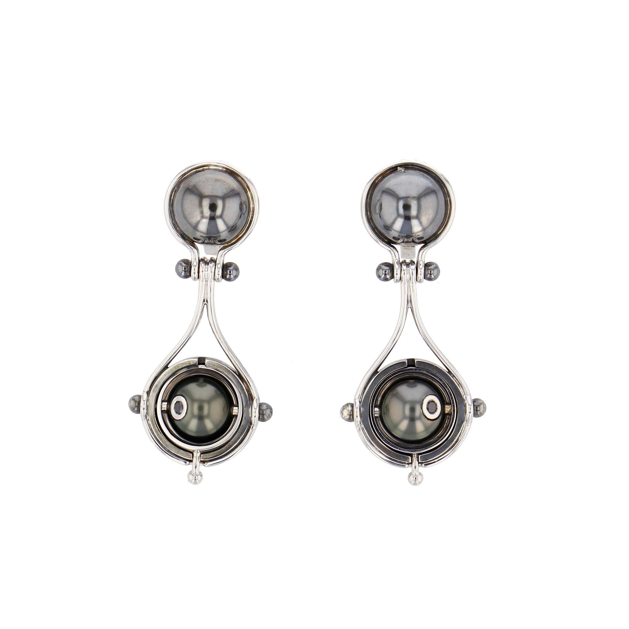 Earrings Pluton White Gold Silver Tahiti Pearl Diamonds

Dangly clip-on earrings comprising two white gold threads around a patinated silver globe level with the ear. This supports a patinated silver mobile structure, on which a rotating white gold
