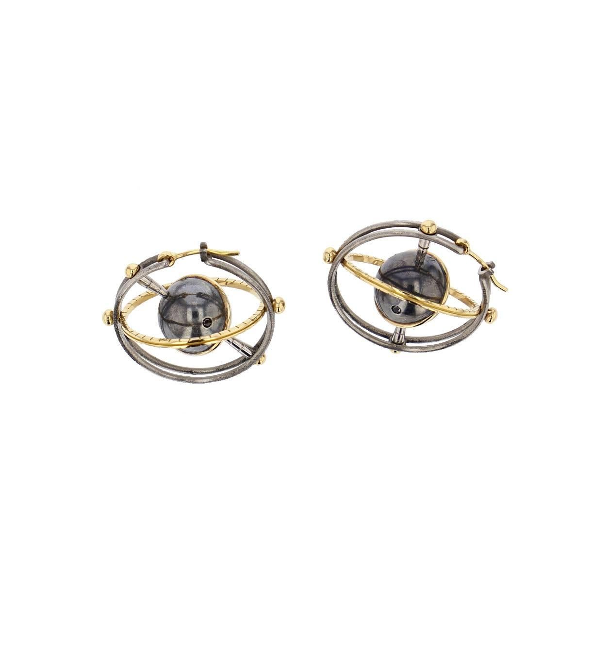 Earrings Mir Gold Silver Diamonds

Creoles made of two polished steel bands holding a rotative system with a white gold axis carrying a white gold and patinated silver globe, circled in yellow gold. This moving planet is set with white and black