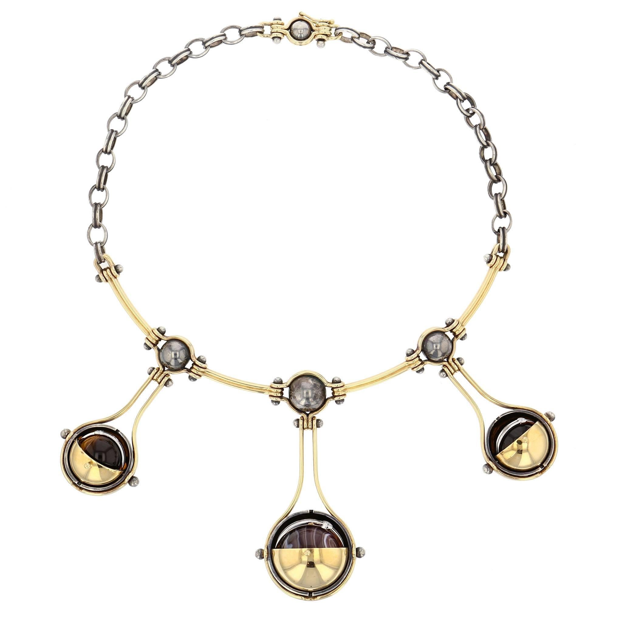 Elie Top 3 Drops Necklace Gold and Diamonds

Choker comprising a yellow gold articulated torc and a patinated silver chain. The three drops are made of two yellow gold threads around a patinated silver globe supporting a mobile structure. This in