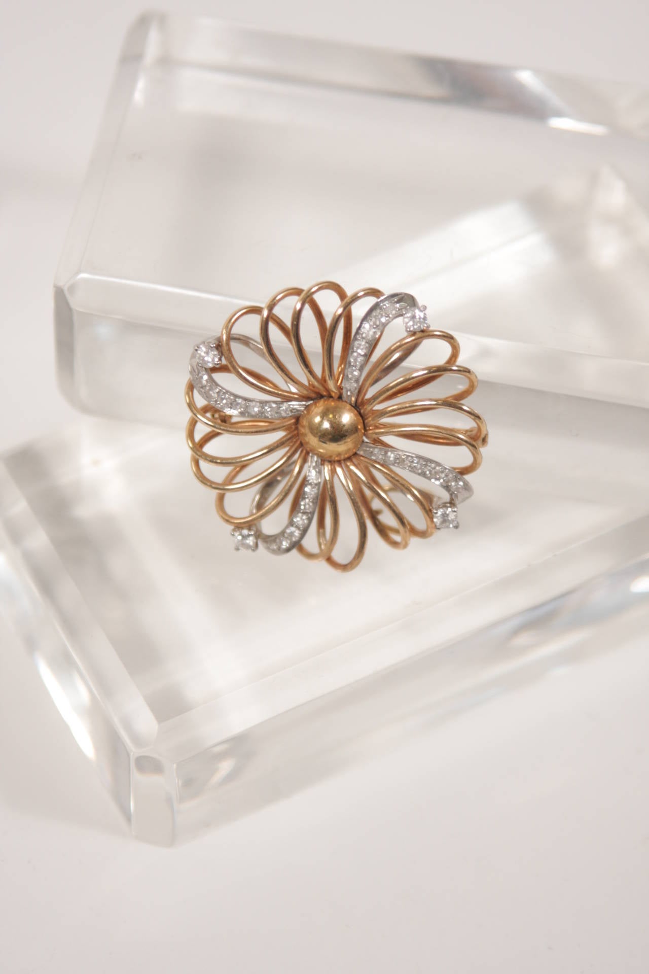 This brooch is available for viewing at our Beverly Hills Boutique. The brooch is composed of 14k yellow and white gold with diamonds. It features an abstract floral design. Measures 1 3/8