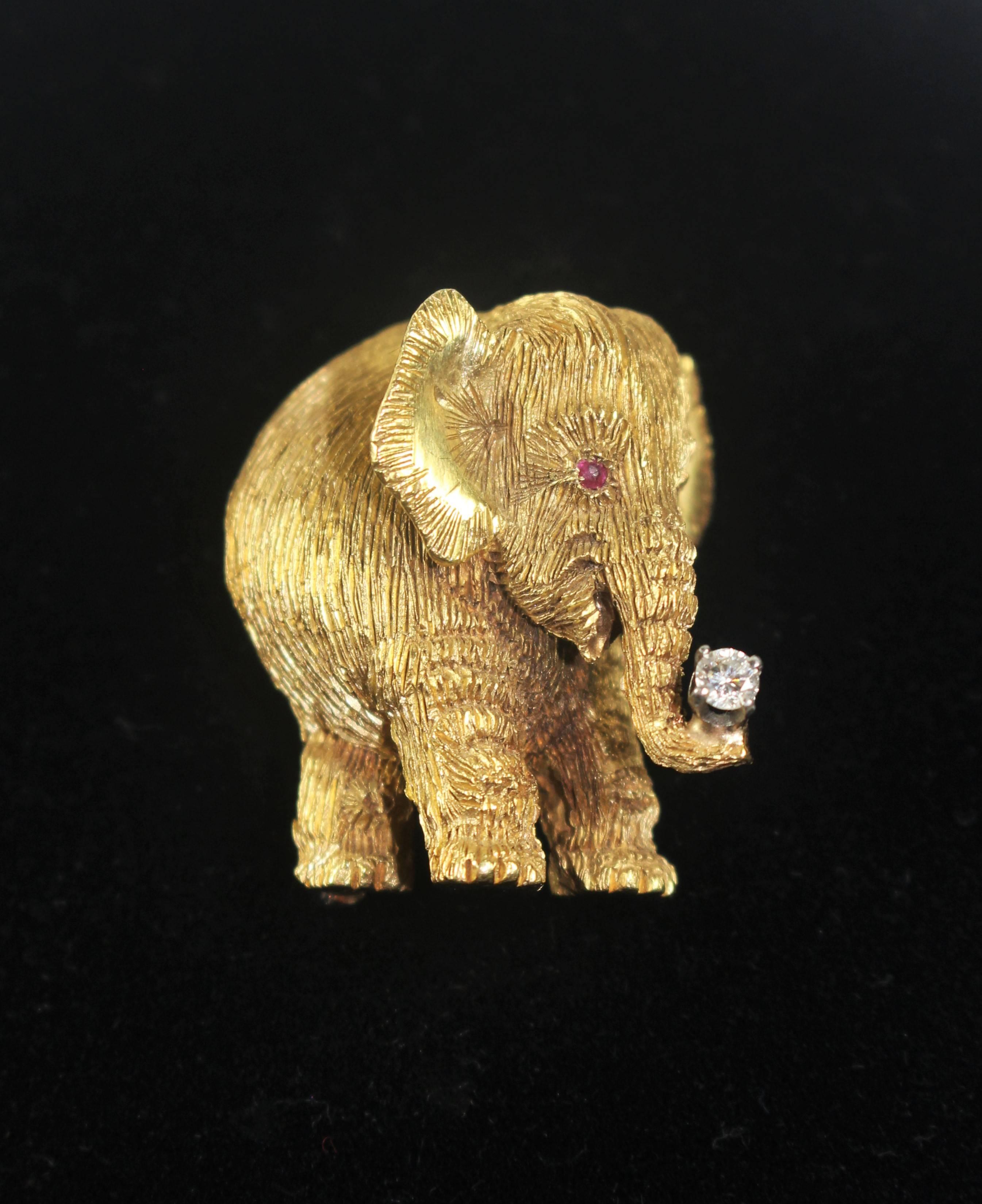 This pendant is composed of 18KT yellow gold. Features a textured design with a diamond held in the trunk and ruby eyes. Has an optional pin closure. In excellent vintage condition.

Listing is for Elephant only. 

Specs: 
18KT Yellow