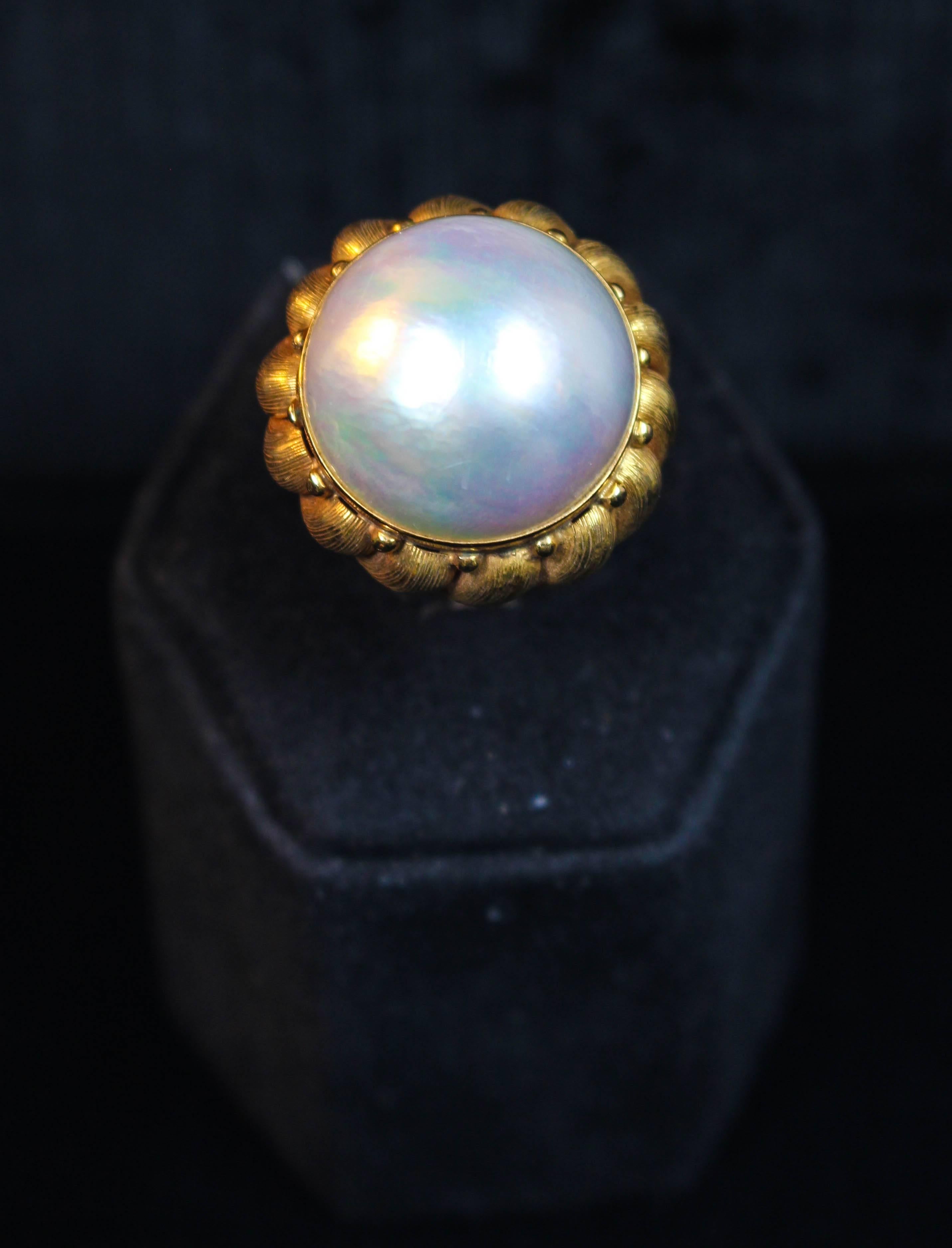 This 1970s Italian Mabe pearl ring features 14kt textured gold and a striking iridescent sheen. Specs below. In excellent condition.

Please feel free to ask any questions you may have, we are happy to assist. 

Specs:
14 KT Yellow