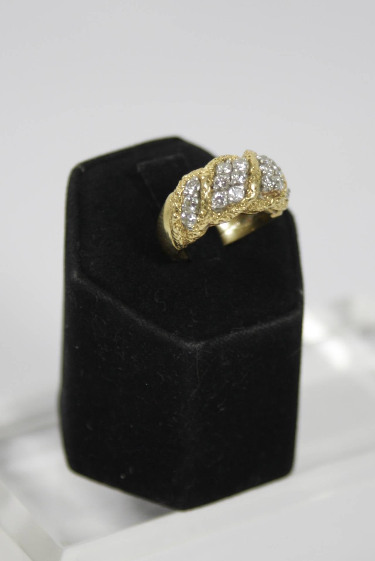 The ring is composed of a textured 18KT yellow gold and features brilliant cut diamonds. Approximately a size 5, can be sized. 

Specs:
18 KT Yellow Gold
Diamonds: 18 brilliant cut diamonds  with an approximate total weight of 1.00 carats
Gold: