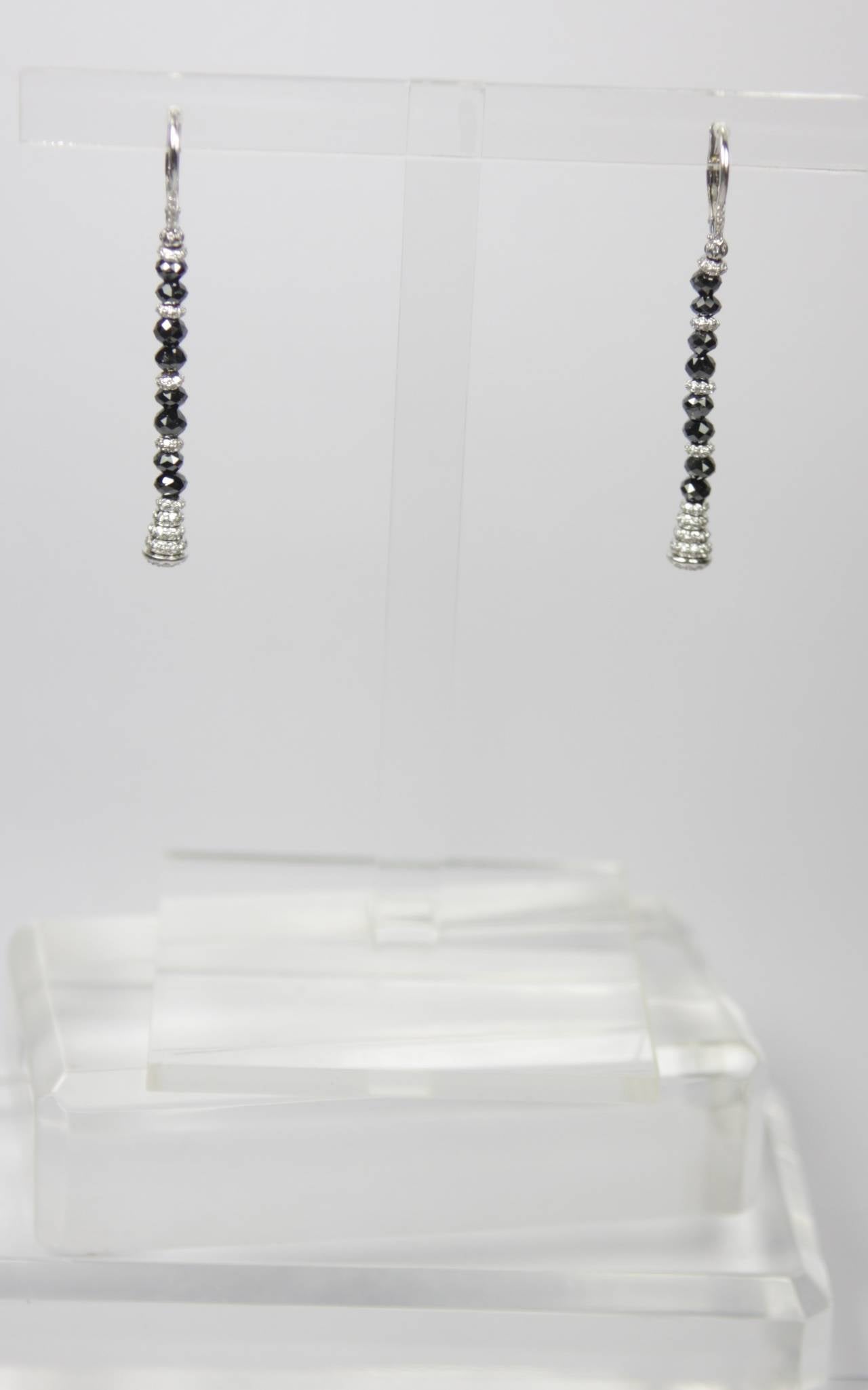 These earrings are composed of 18kt white gold and feature rose cut black diamonds and round cut white diamonds. Drop style with hinge closure.

Specs: 
18 KT White Gold 
Diamonds: 1.55 Carats Approximate Total Weight
Measures: 2.25