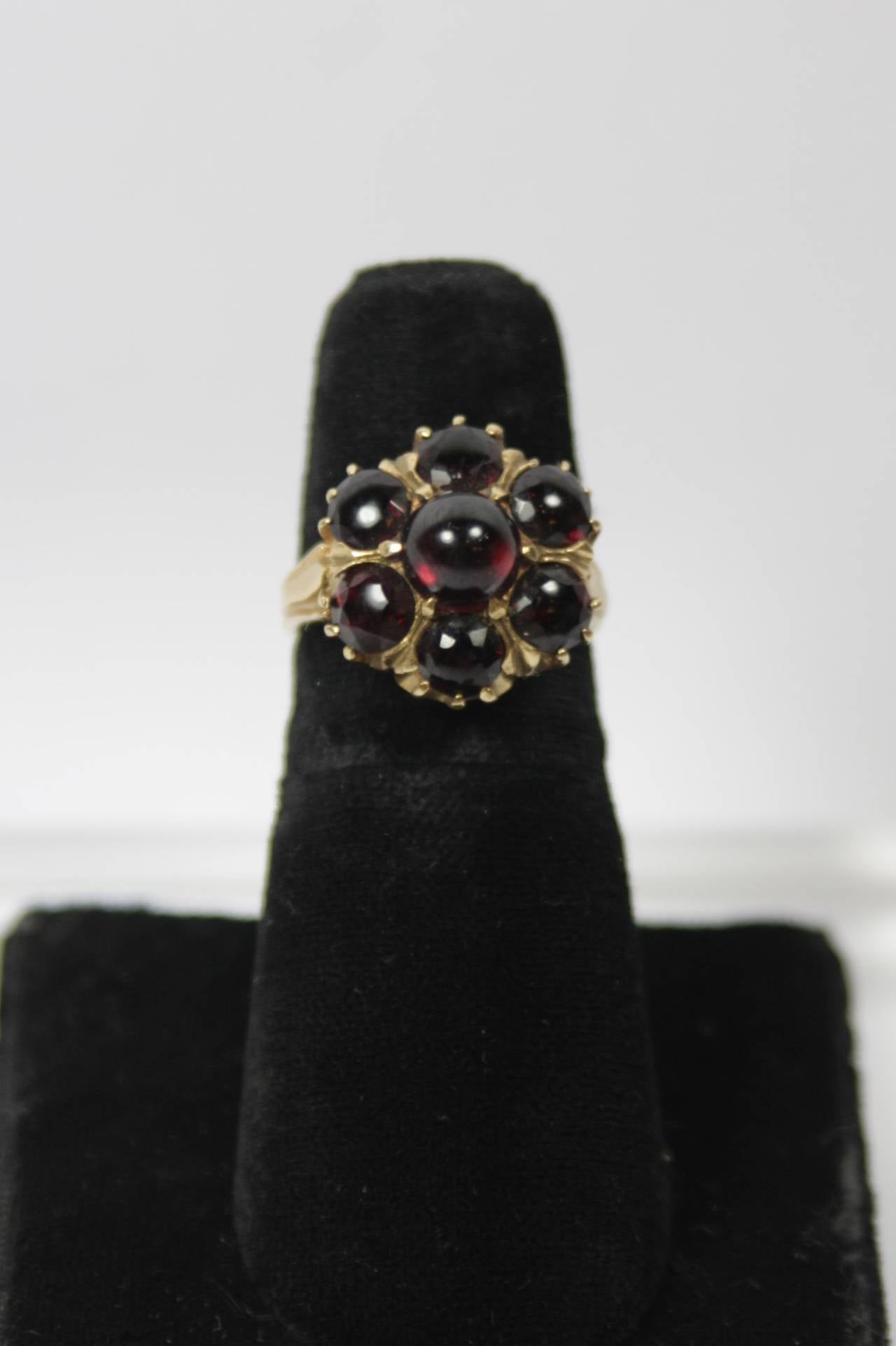 This Garnet ring features seven Cabochon cut garnets set in 14KT gold. A stunning ring in excellent condition.

Specs: 
Garnet: 7 Cabochon cut
14KT Gold 
Measures: .5" Width across face
Approximately size: 6.5
