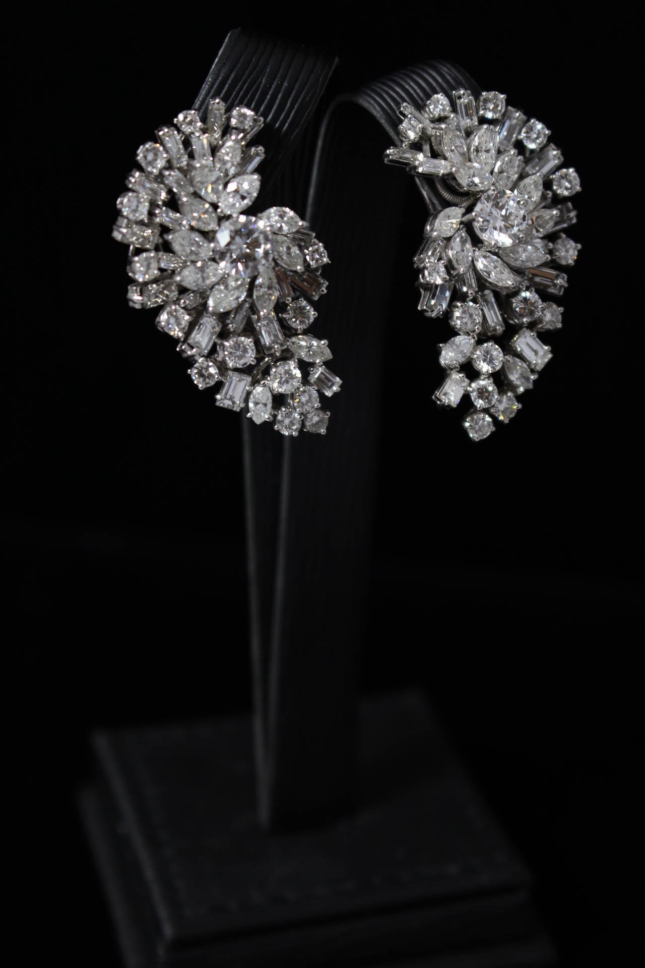 These are a gorgeous pair of platinum and diamond earrings. The earrings display 94 diamonds with an approximate total weight of 14 carats. There are approximately 40 Square, 24 Pear, and 30 Round cuts. These earrings feature a clip closure (which