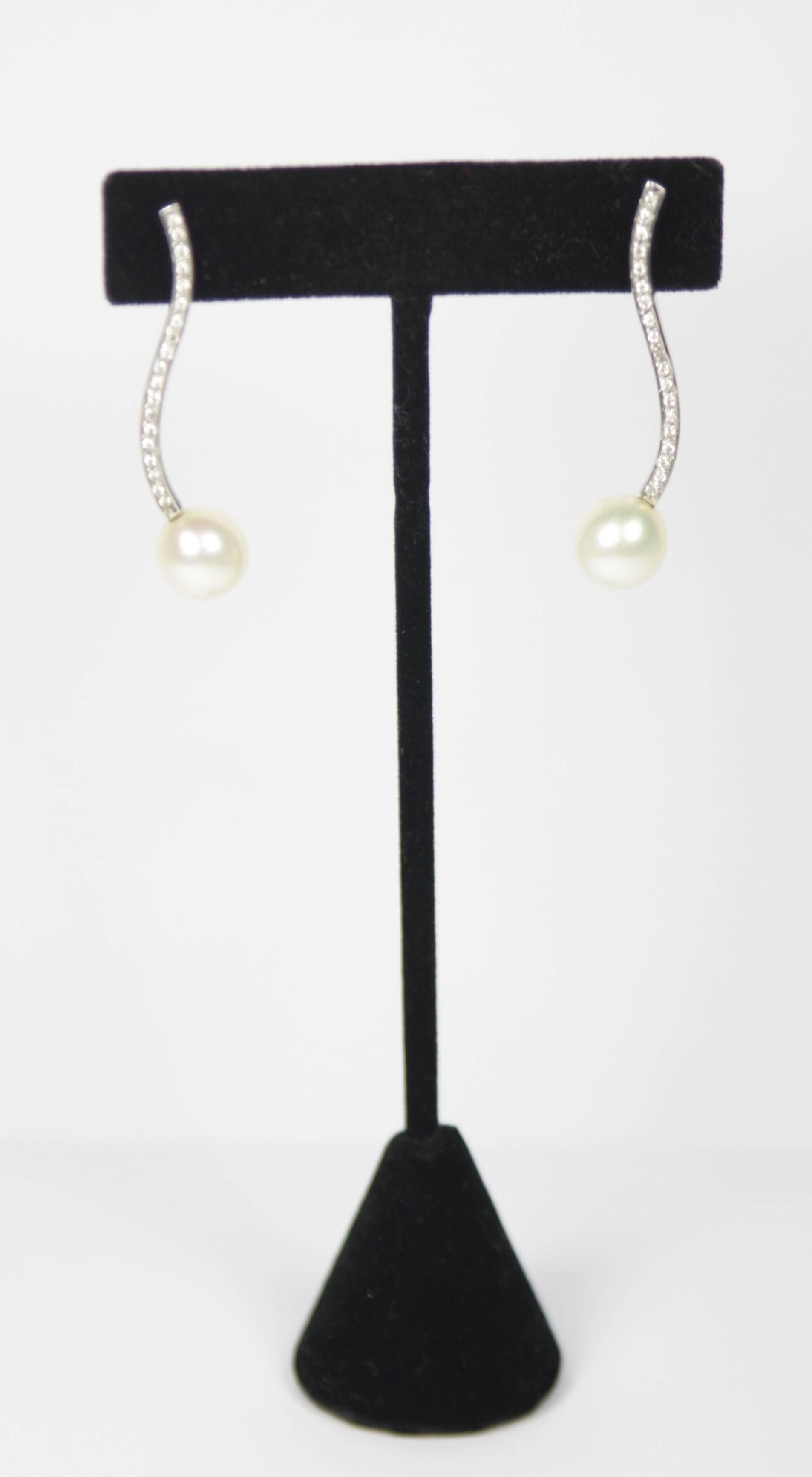These pearl and diamond earrings are composed of 14kt white gold with pave diamonds featuring 10.2mm pearls.

Specs: 
14 KT White Gold 
Measures: 
1 5/8