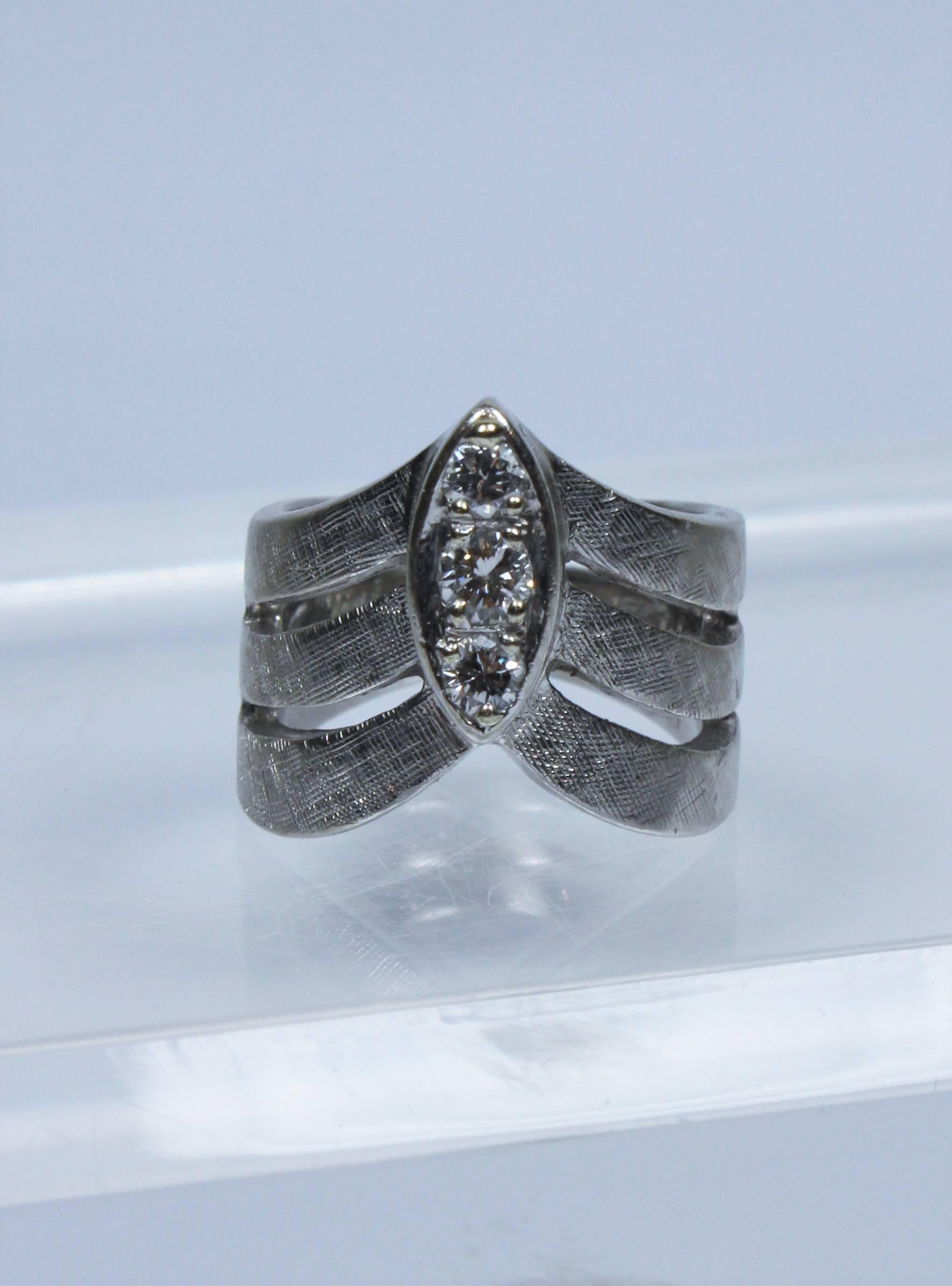 This vintage ring is composed of a textured 14KT white gold featuring three center diamonds and a pointed chevron design. 

Specs: 
14KT White Gold 
Height 3/8