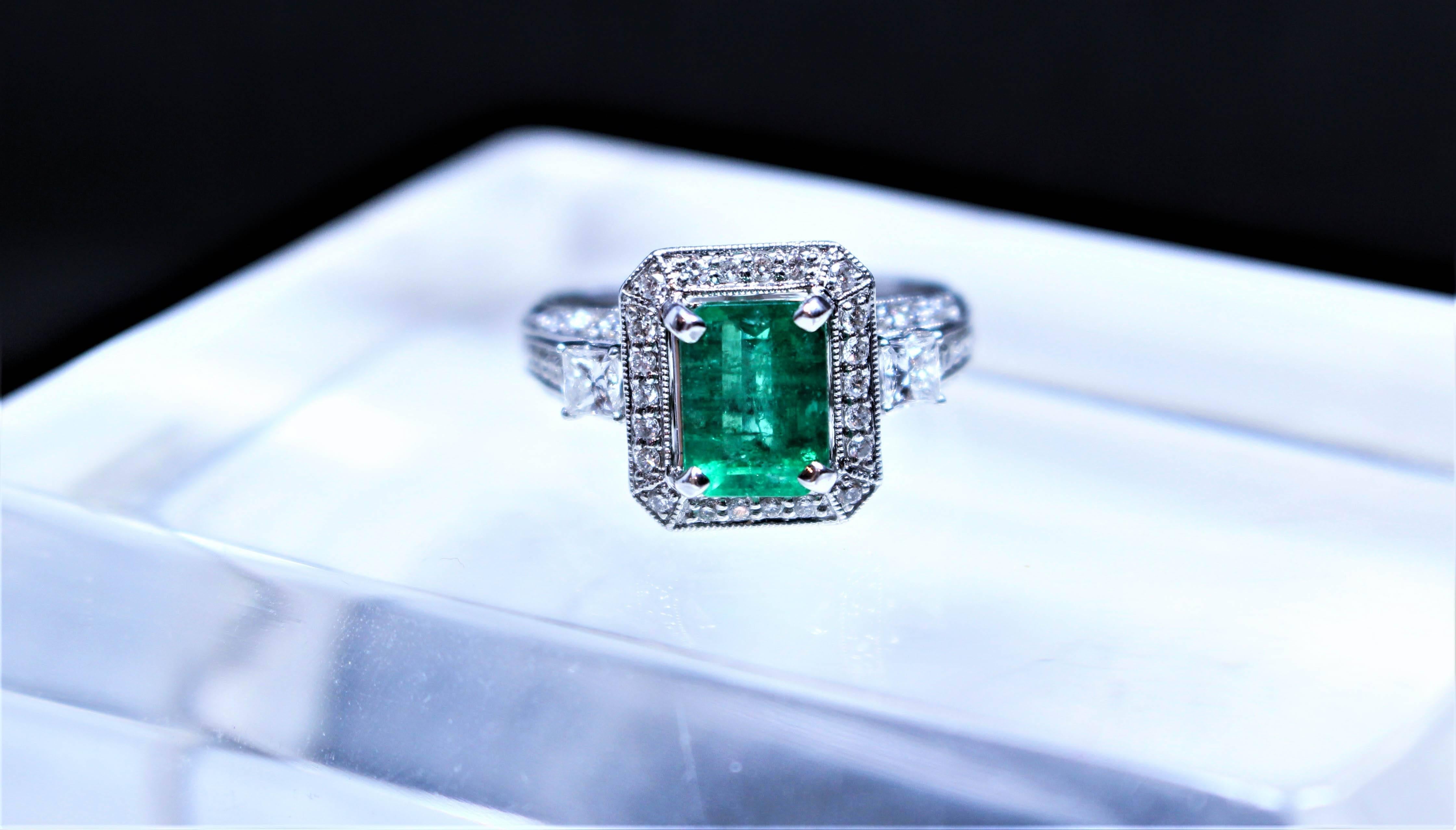 This ring is composed of 18kt white gold and features a stunning Emerald center stone with an approximate 1.92 carats. The filigree setting boosts approximately 68 round cut pave diamonds and two larger square cut stones flanking the center stone.