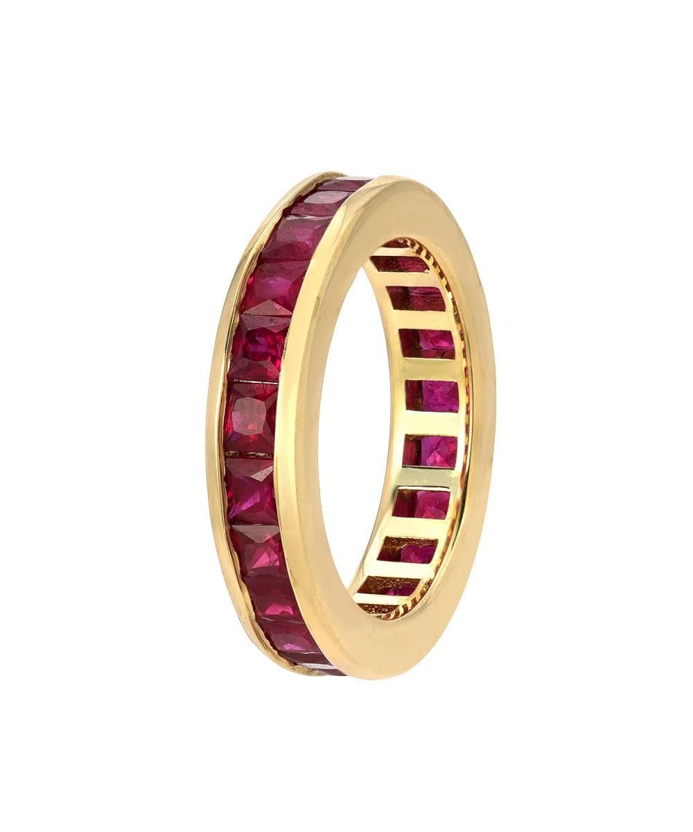 This simple eternity band is crafted in 14 karat yellow gold and features over 4.5 carats of matching 3 mm princess cut rubies. The ring is a standard US size 7 and is designed to have a unique tall and bulky mounting which lays comfortably in