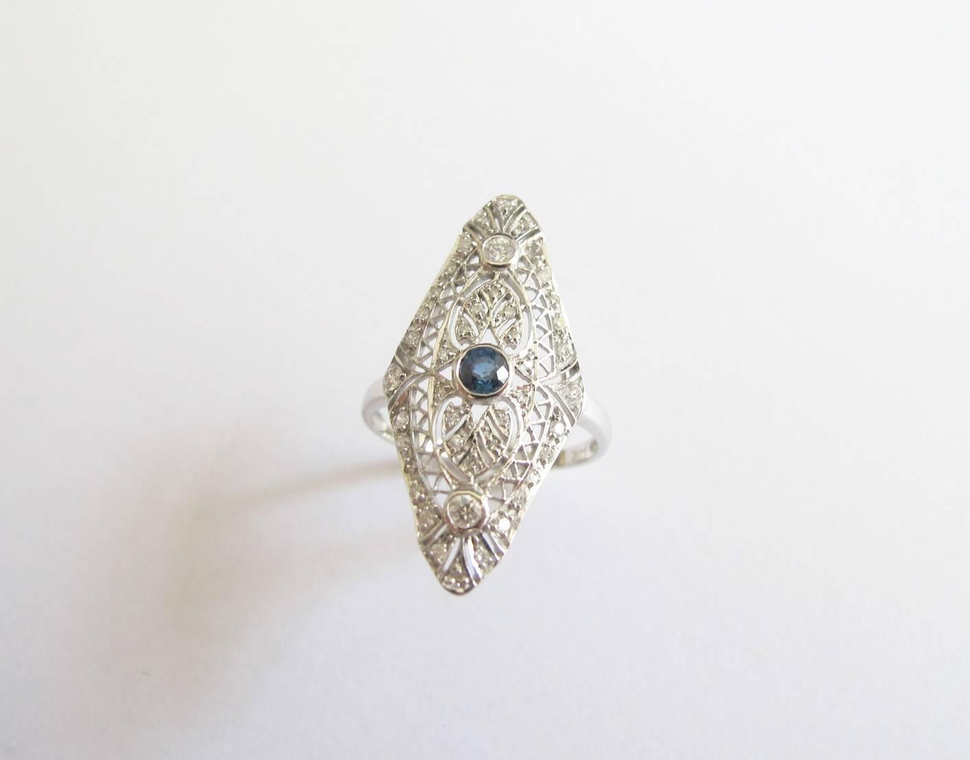 Reproduction of an antique-style cocktail ring, made in 14K white gold with one central sapphire and surrounding diamonds set in the detailed filagree.  A delicate and feminine piece.

Ring size: 6.5
Sapphire weight: 0.25ct
Diamond weight: 0.40ct
