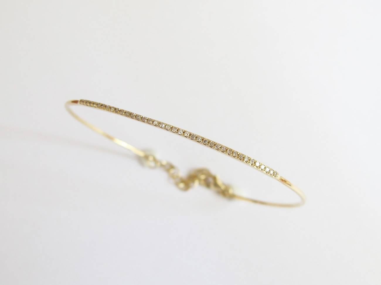 This thin and delicate 14K yellow gold pavé diamond bangle is perfect on its own or stacked with other bracelets.  The bangle has an extension (1.3 inches) and clasp to accommodate different wrist sizes.  

Diameter: 60mm X 51mm
Diamond weight: