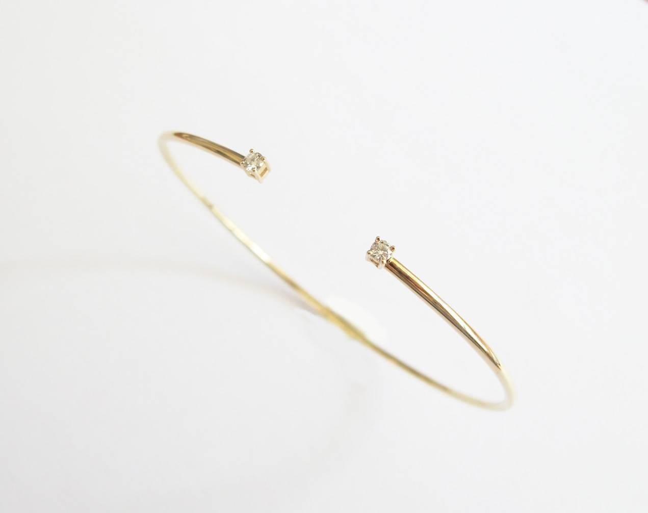 This delicate flexible bangle is made in 14K yellow gold with two prong set diamonds at the opening of the cuff.  A simple and elegant bangle to wear on its own or a great addition to a stack of bangles.

Diameter: 60mm X 48mm
Diamond weight: 0.10ct