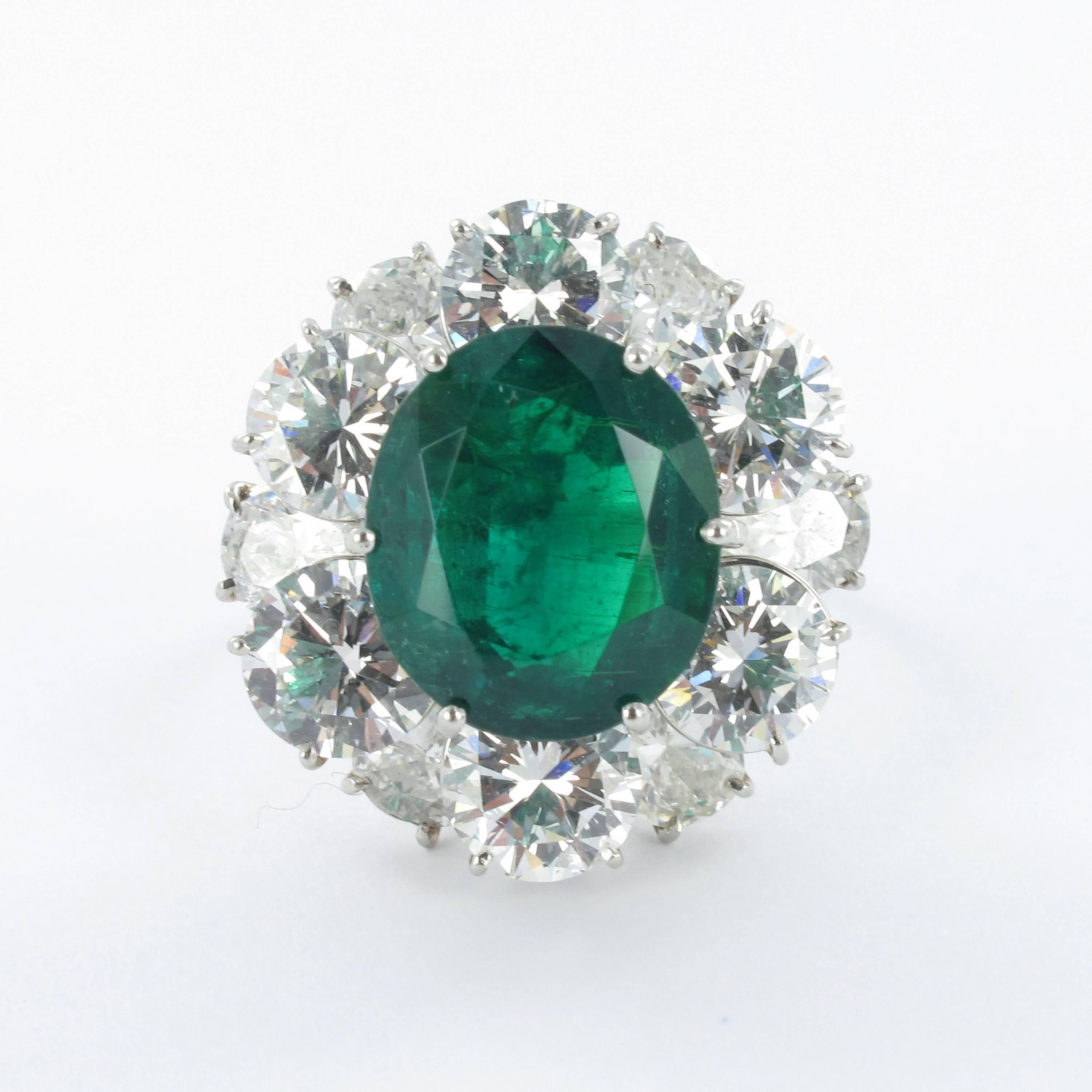 Emerald and diamond ring. Set with an oval shape Colombian emerald with a weight of approximately 5.50 carats, encircled by six brilliant cut diamonds, total weight approximately 4.70 carats (G/H colour and vs clarity) and six pear shape diamonds,