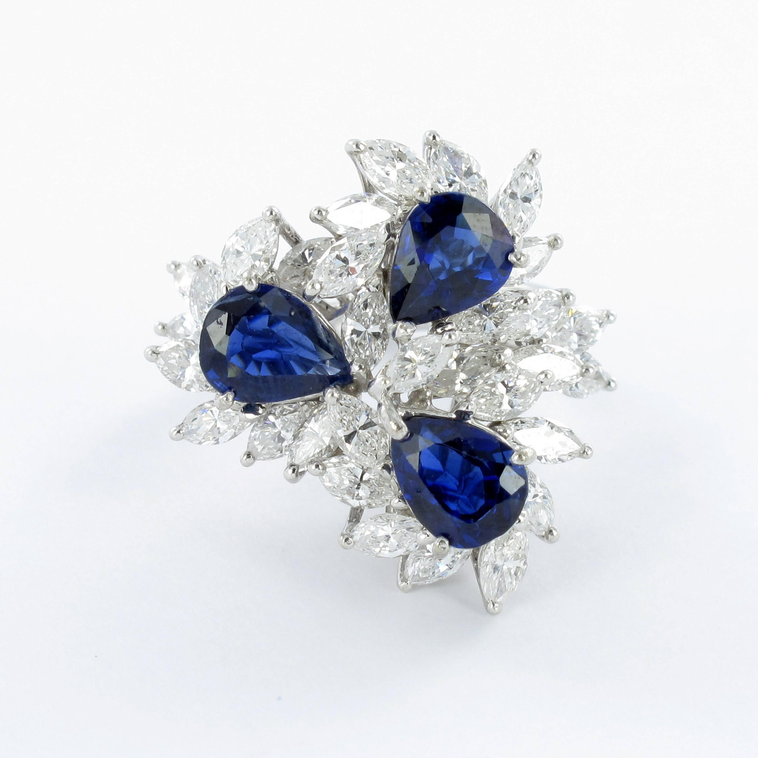 Cluster ring in white gold 750. Prong set with three blue, pear shape cut sapphires facing each other. Measurements of the sapphires are approximate 7.5 x 6mm, totaling in 3.30 ct of weight. Each sapphire is surrounded by marquise cut diamonds,