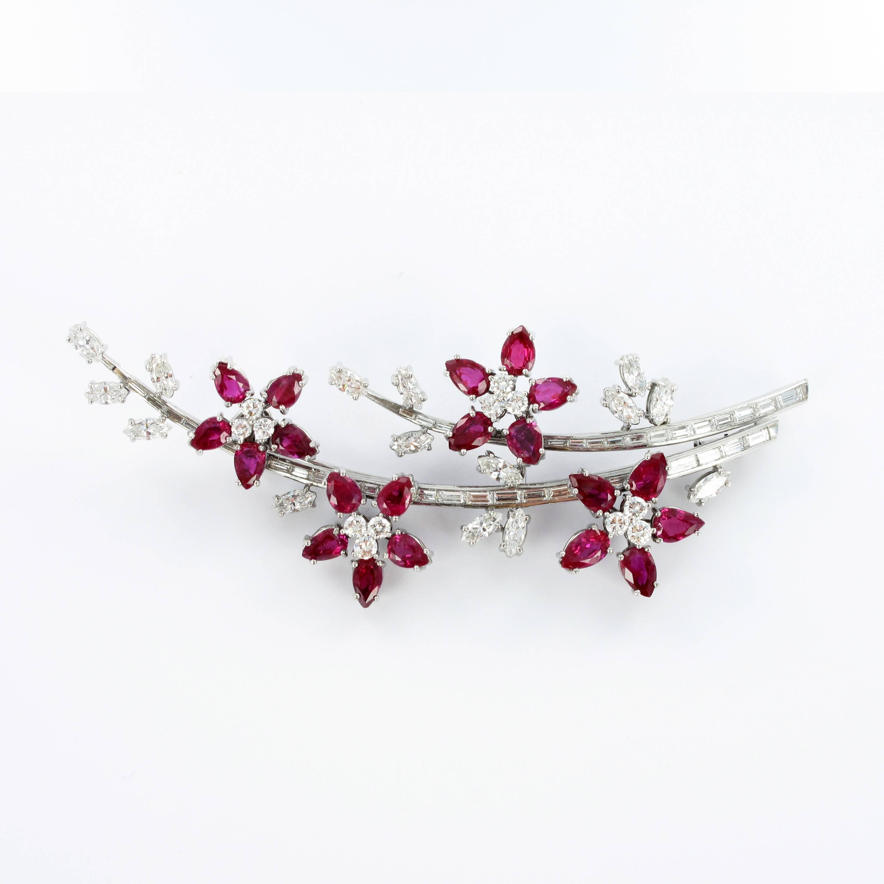 Brooch resembling two flower stalks decorated with four blossoms and leaves. Very finely crafted in platinum 950.
Each blossom is prong set 5 Burmese pear shape rubies and 3 brilliant cut diamonds. The two stalks are chanel set with 36 baguette cut