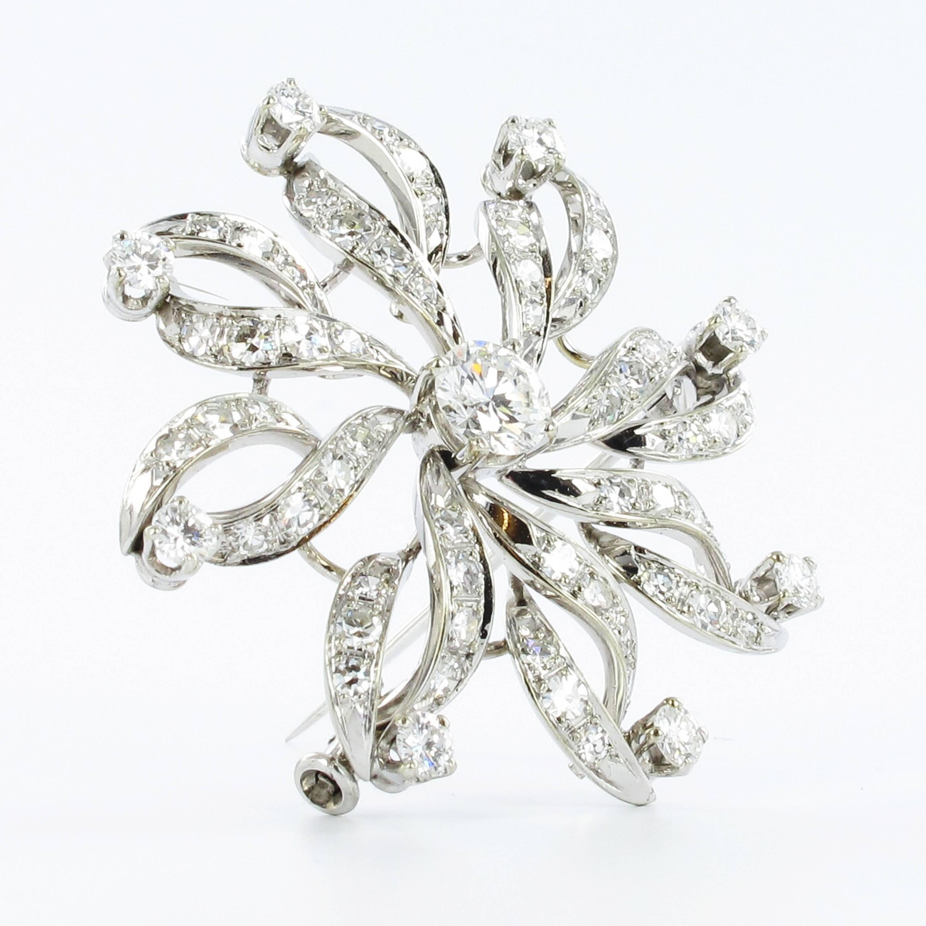 Designed as a wind wheel, this Gübelin brooch in white gold 750 sparkles with 9 brilliant-cut and 56 single-cut diamonds. Center stone with a weight of approximately 0.60 carats (E/F colour and vs clarity), entourage with a total weight of