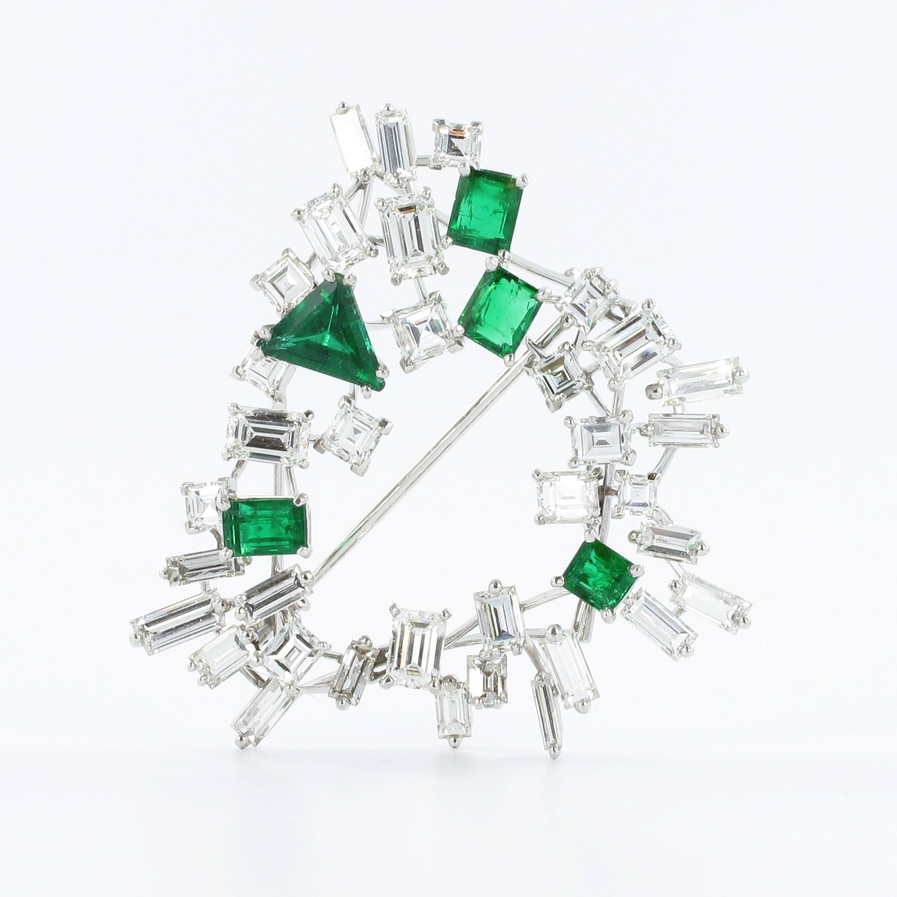 Beautiful brooch in white gold 750. Prong set with 35 square, baguette and emerald cut diamonds of F/G colour and vs clarity, total weight approximately 8.00 carats. Accentuated by 5 emeralds, total weight approximately 2.60 carats. Approximately 45