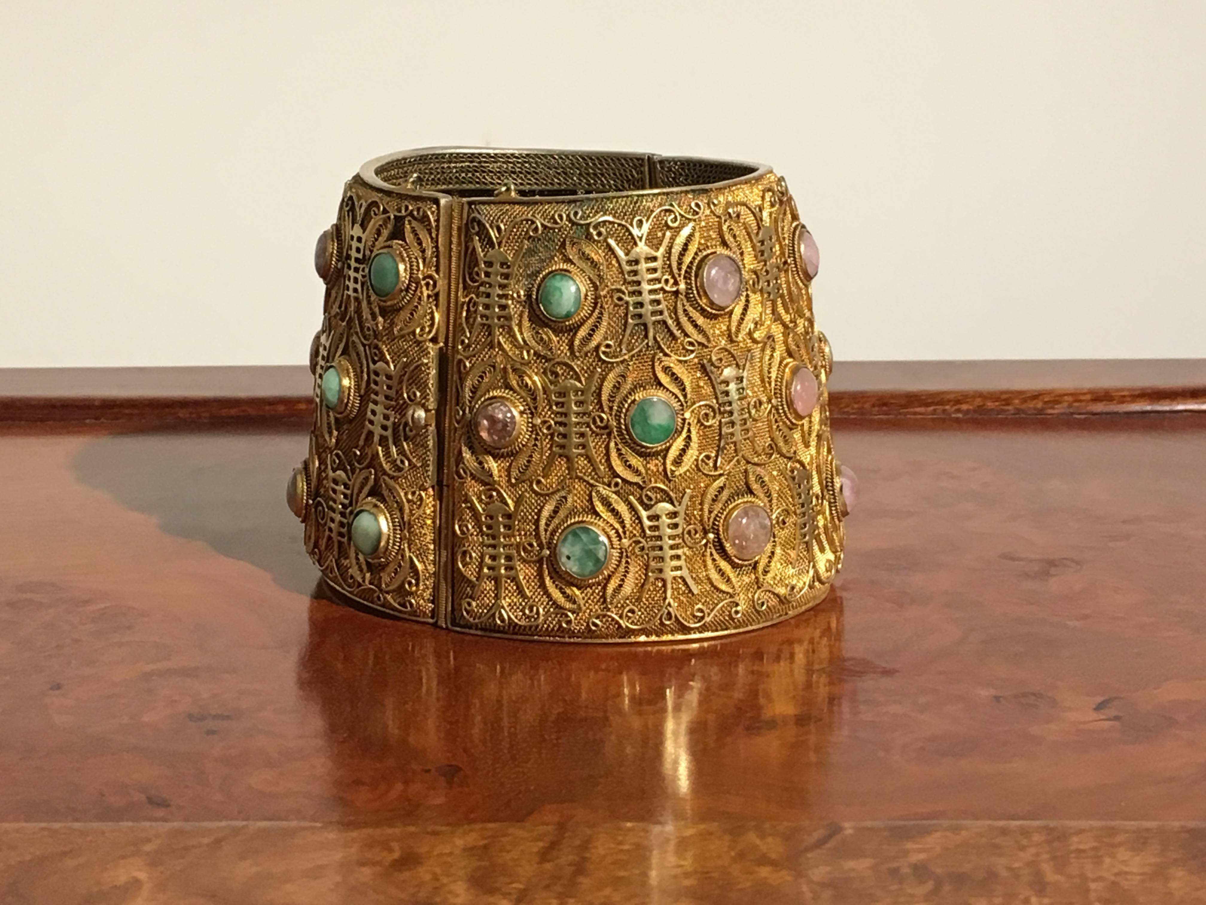 A large and stunning Chinese export vermeil cuff set with jade and tourmaline. The cuff of finely worked woven gilt silver, with a stylized butterfly design throughout. The bodies of the butterflies designed as "shou" (longevity)
