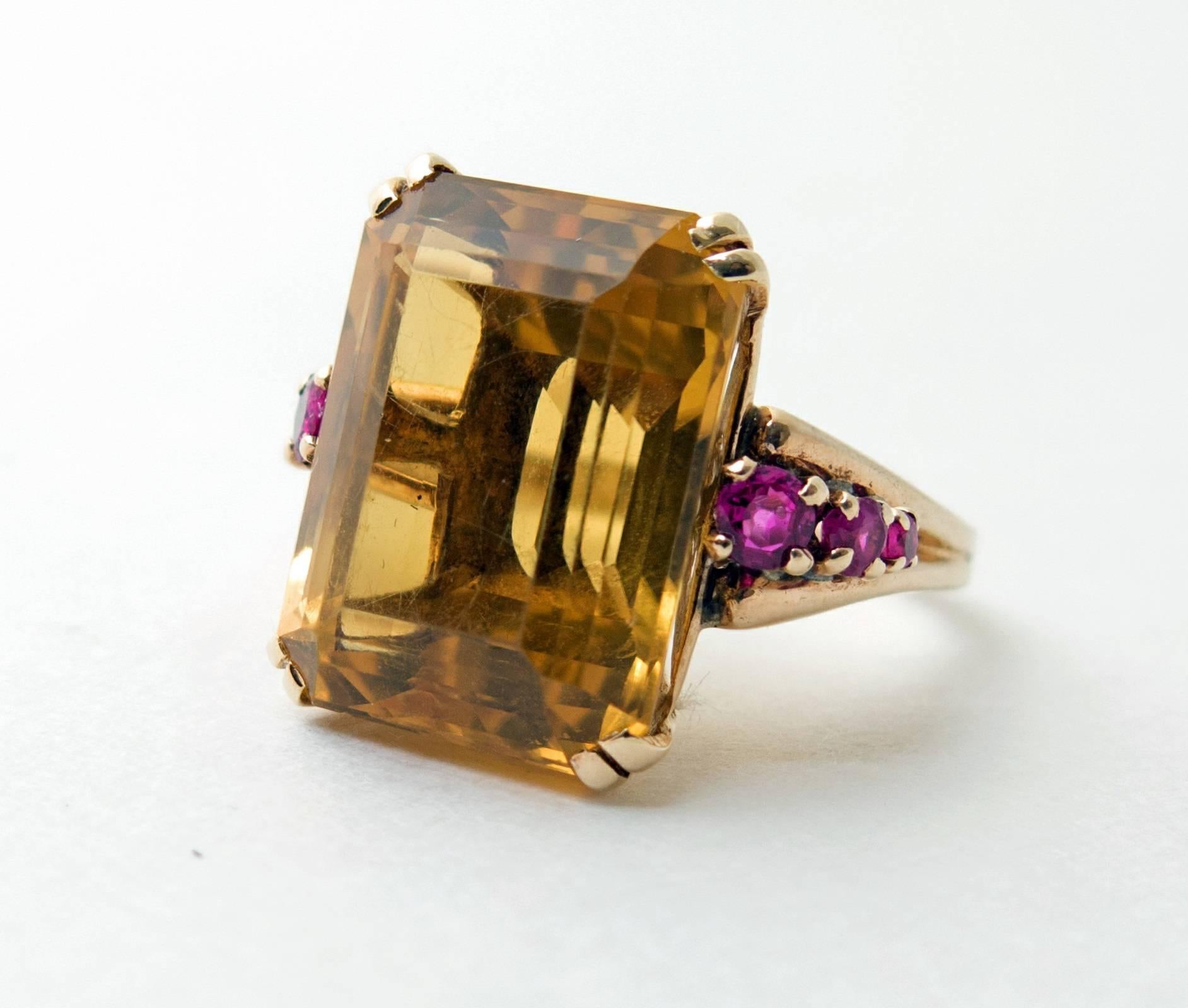 A classic and stunning Retro, 1950's ring, featuring a large 18.18ct. emerald cut citrine of good yellowish orange color. Set in 14k yellow gold with six rubies as accents. 