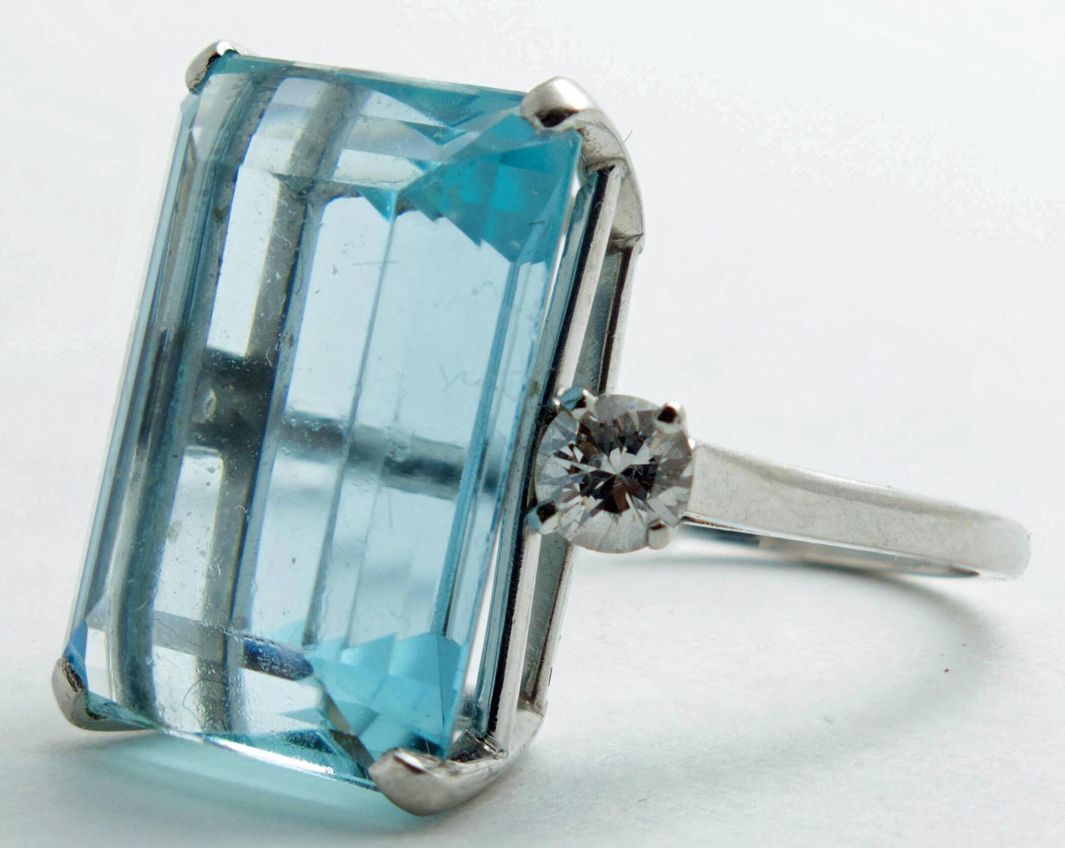 A classic emerald cut aquamarine weighing approximately 15.29 carats with a round brilliant cut diamond on either side total combined weight of approximately .50 carat (H-I color, VS clarity) and with a thin polished shank, stamped PLAT. Dated to