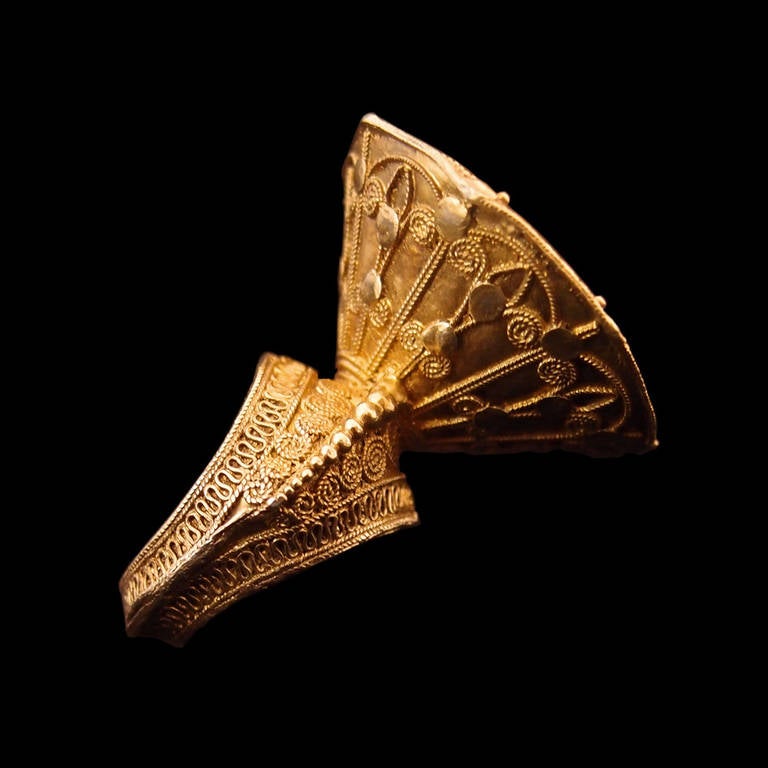 A finely worked gilt silver ring from the Karo Batak people of Sumatra, Indonesia. The high set octagonal face featuring highly detailed geometric and flori-form designs worked in filigree and granulation, the sides tapering to attach to the band. A