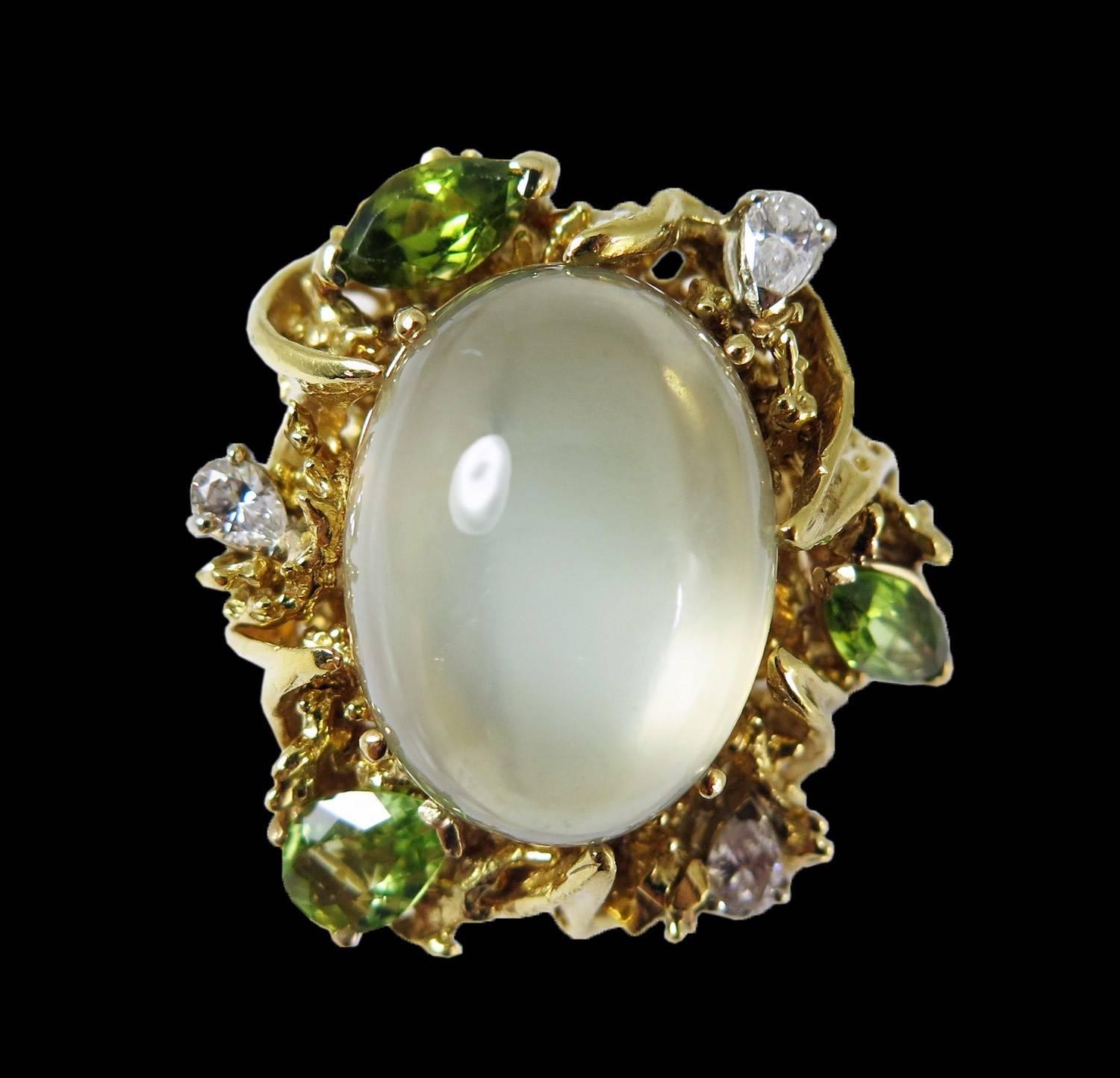 An impressive 1960's 18k yellow gold free-form ring centered around a large cabochon moonstone with a milky translucency.
The large 19ct cabochon moonstone is surrounded by diamonds and green peridot, all set in a handcrafted organic free form