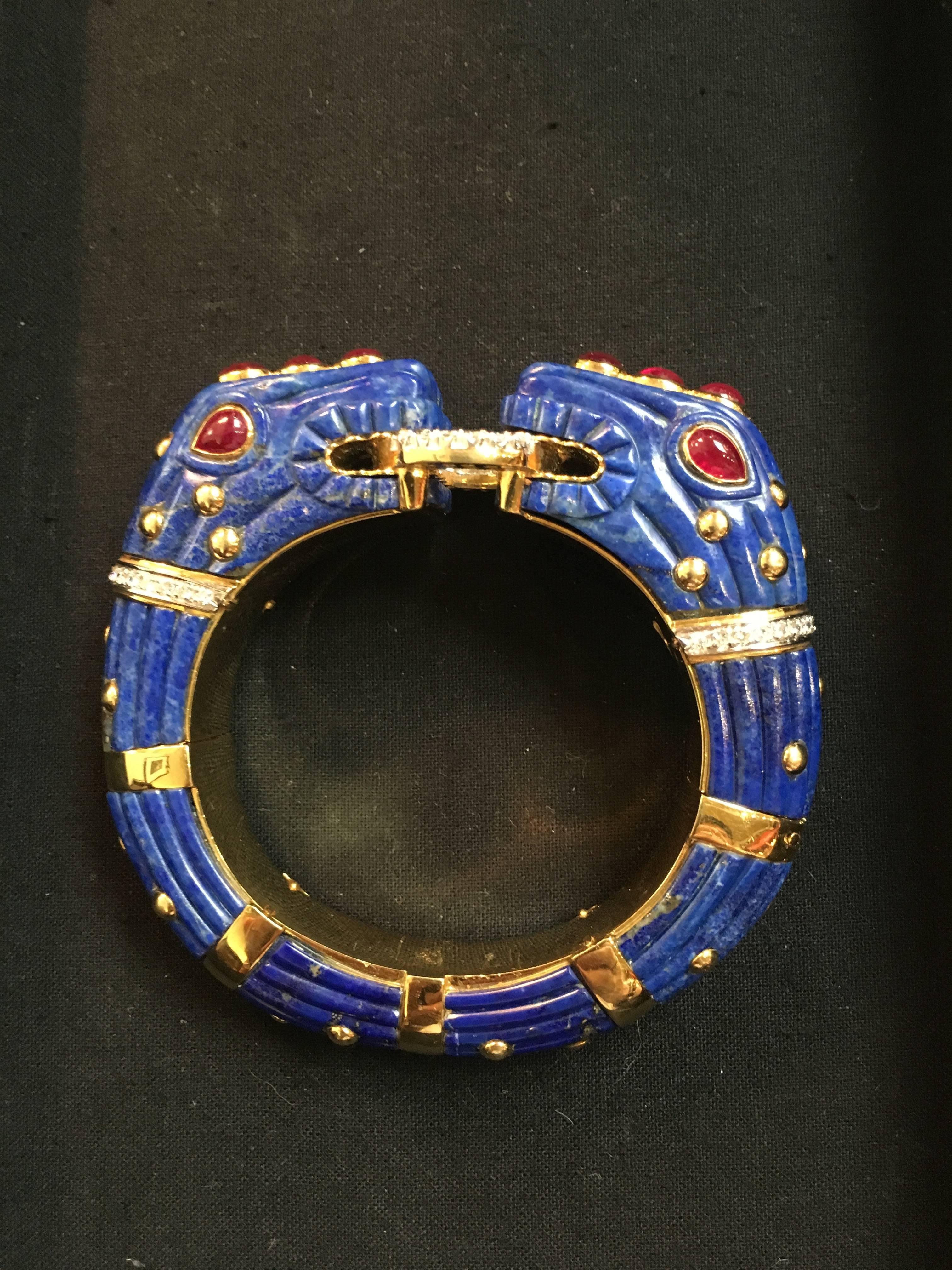 A stunning lapis, diamond and ruby bracelet featuring a pair of chimera heads holding a diamond encrusted ring. The lapis studded with 18k gold "spots". Each head with large ruby cabochon eyes and a crown of three ruby cabochons on a pave