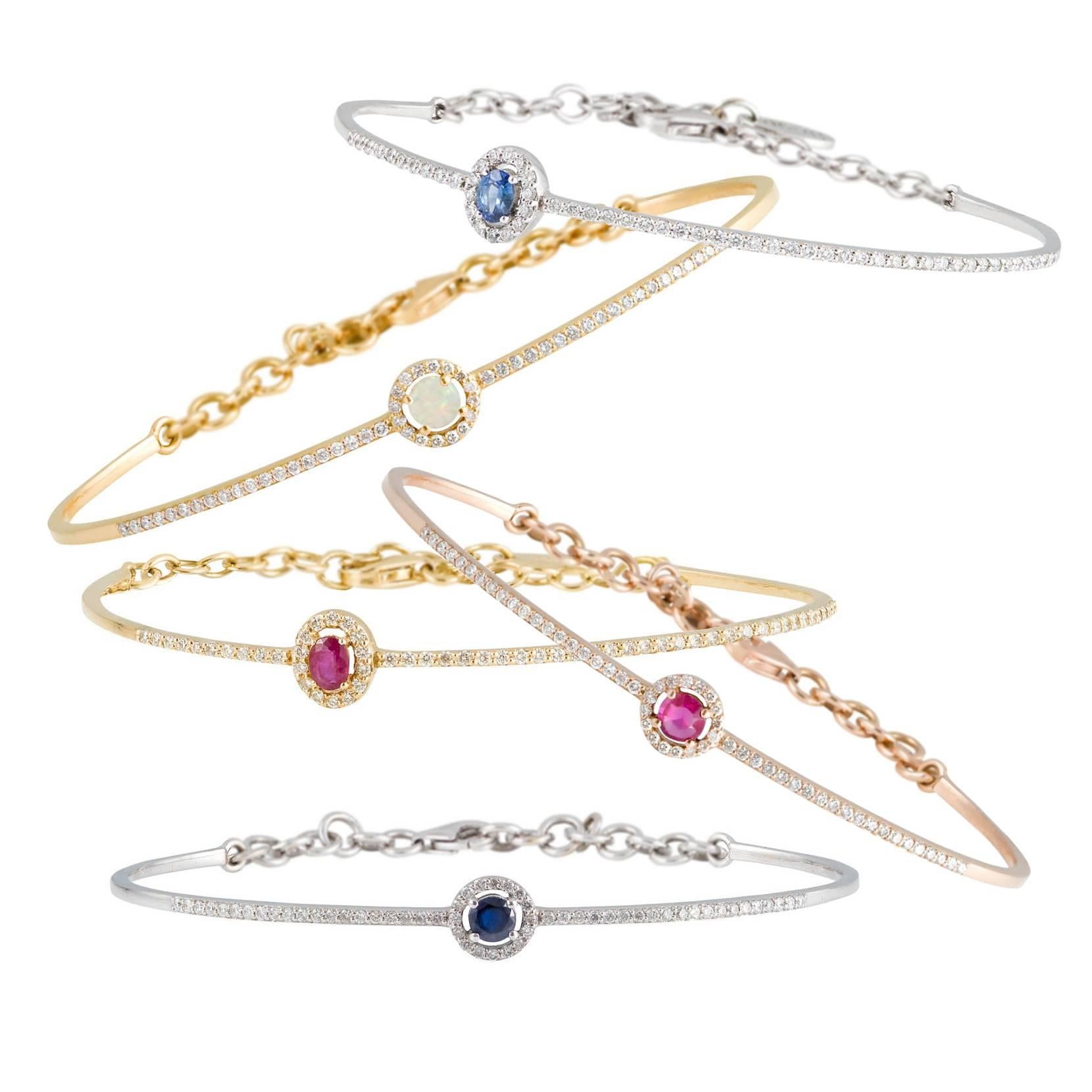 A Diamonds set and Opal accented Rose Pink Gold bangle bracelet. The Ellipse bangle is a delicate and unique design simply by setting the oval diamond halo surrounded gemstone off-center to the bangle. This detail makes a dynamic design and