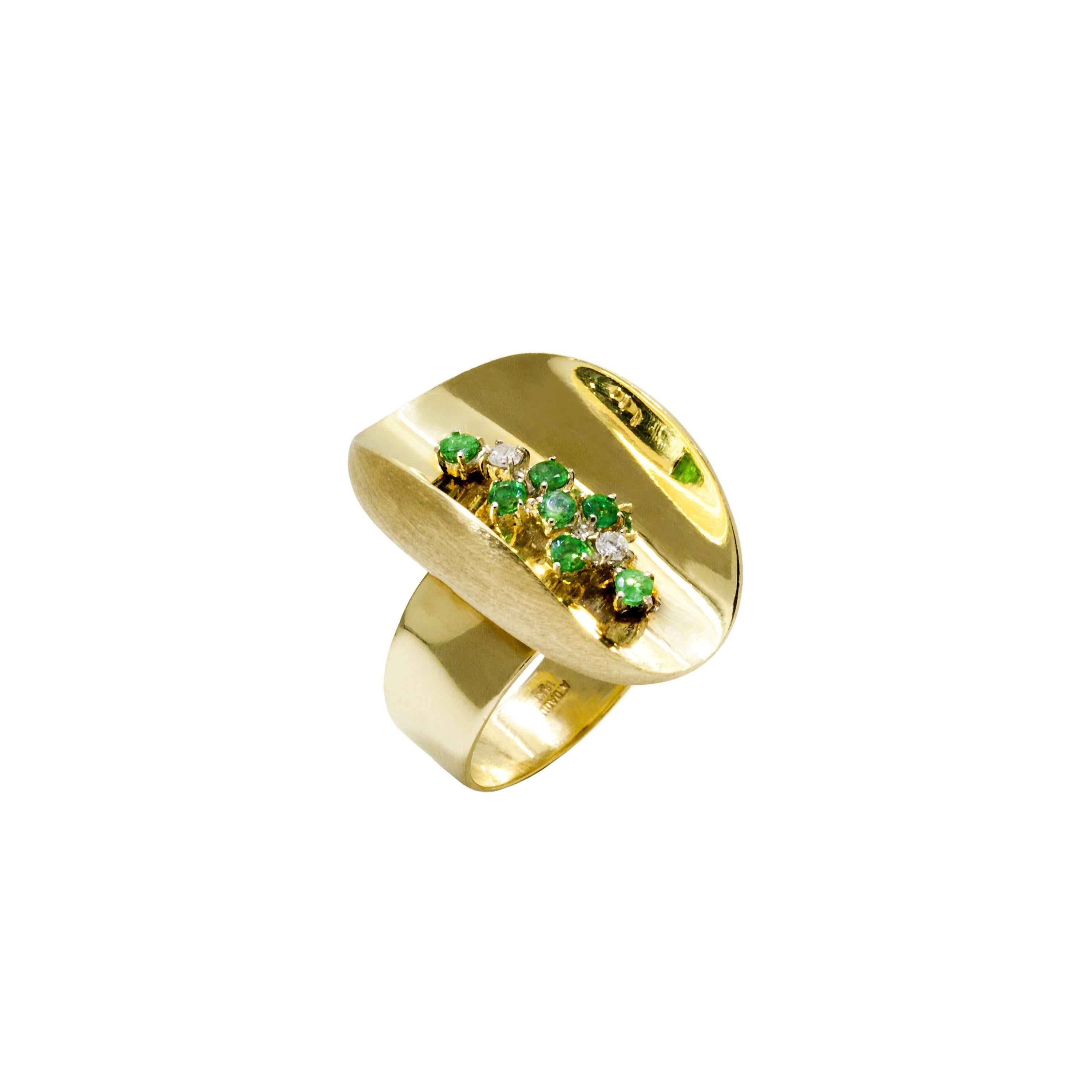 A Diamond and Emerald set handmade Yellow Gold Ring. A striking miniature sculpture, the Ellipse rings feature concave highly polished surface creating depth and myriad reflections of the delicately set gemstones within. From every view there is an