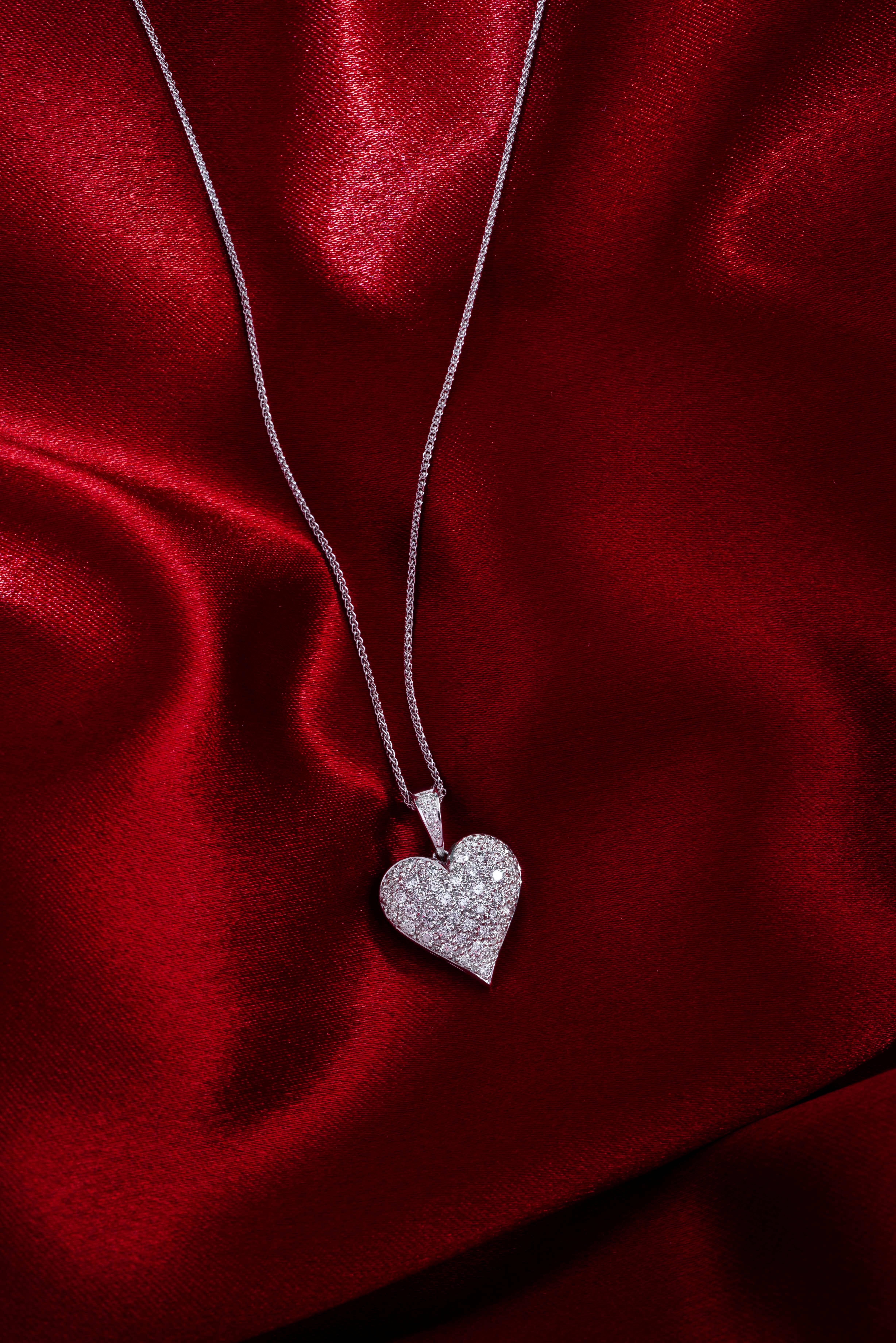 An eternal classic. A full curved beautifully sculpted heart pendant fully pavé set with round brilliant cut diamonds and detail in a diamond set hinged bail chain loop. The Full Diamond Heart has a generously curved rounded surface formed in 18