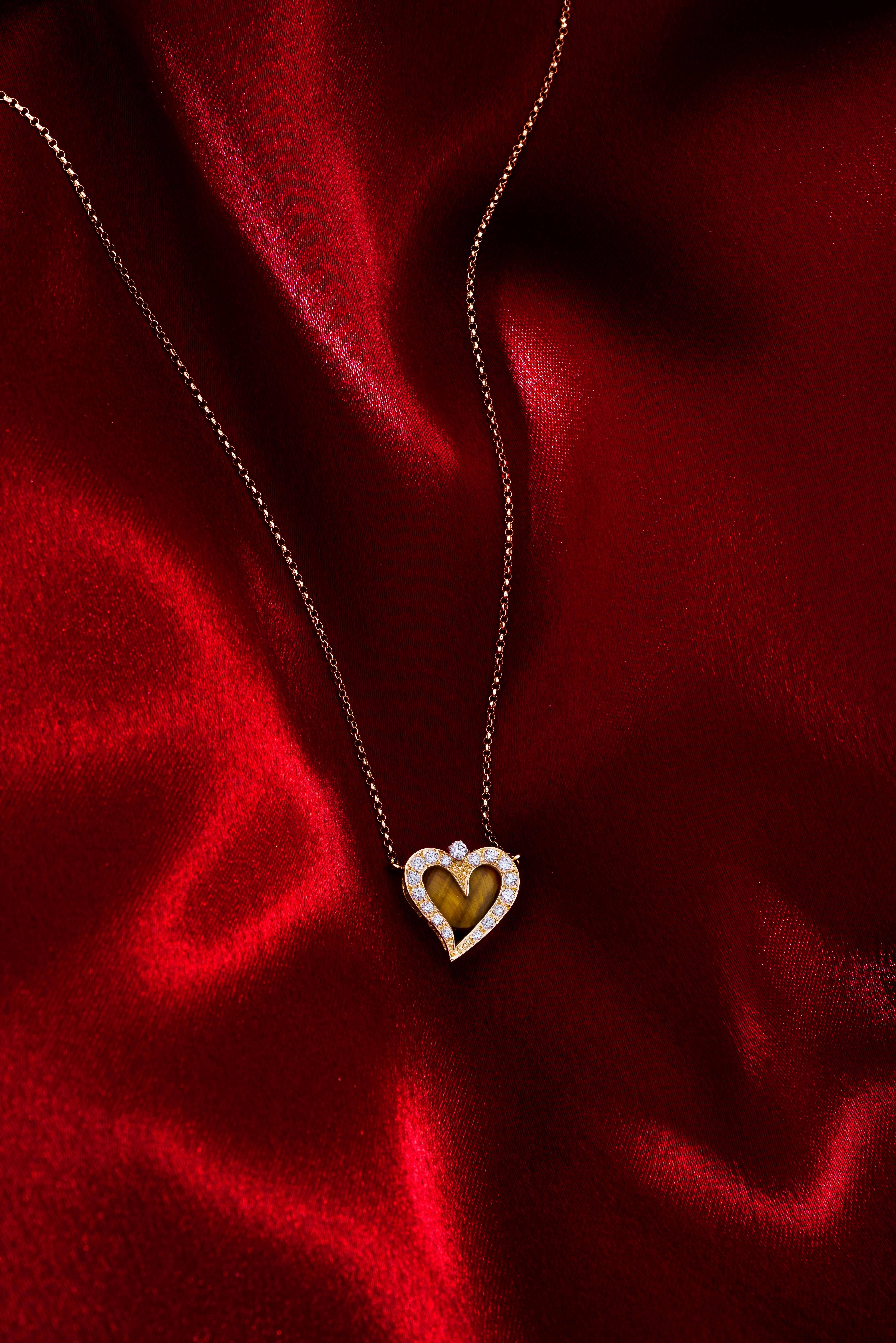 A detailed diamond heart pendant alive with life and happy movement in its shape. Hand made with a special tiered setting made to envelop a special stone center, here a chatoyancy cats eye effect Tigers Eye. A Heart pendant necklace in 18 karat