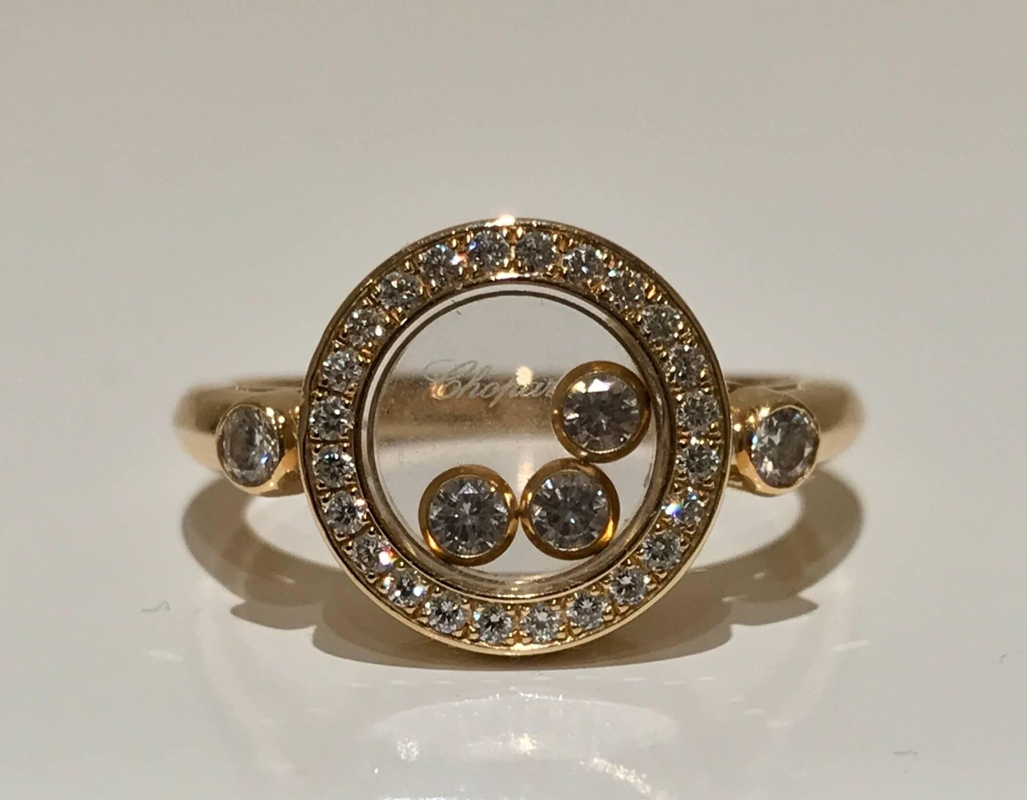 A Chopard Happy Diamonds ring set in 18k yellow gold. The ring features three free moving brilliant cut diamonds under a sapphire glass of appox 0.15 ct and has twenty three diamonds set to circle and two additional diamond set to the edges of the