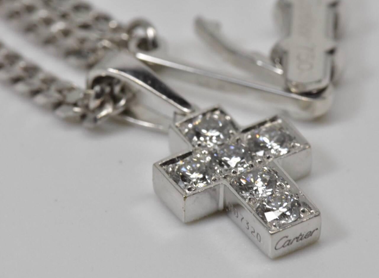 A Cartier diamond cross pendant necklace set in 18k white gold. The necklace features a brilliant-cut diamond cross, suspended from a tapered surmount loop, to the curb-link white gold chain.
Hallmarked: Cartier, ND7320 and HE2461with french