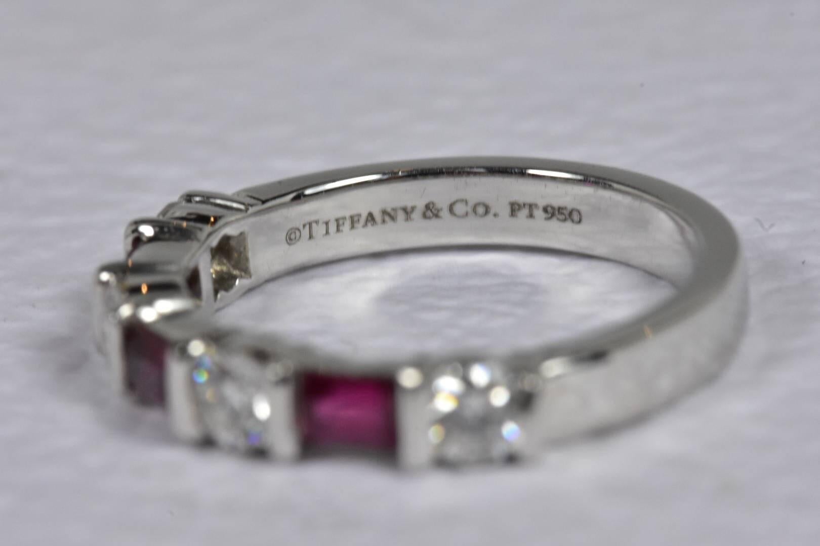 
A Tiffany & Co Diamond and Ruby ring set in platinum. The ring features three baguette cut rubies and four brilliant cut round diamonds set to a plain platinum band. 
Ring size - UK J 1/2 US  4 3/4 EU 49 
Measurements: 3.1mm wide
Gemstones: 3