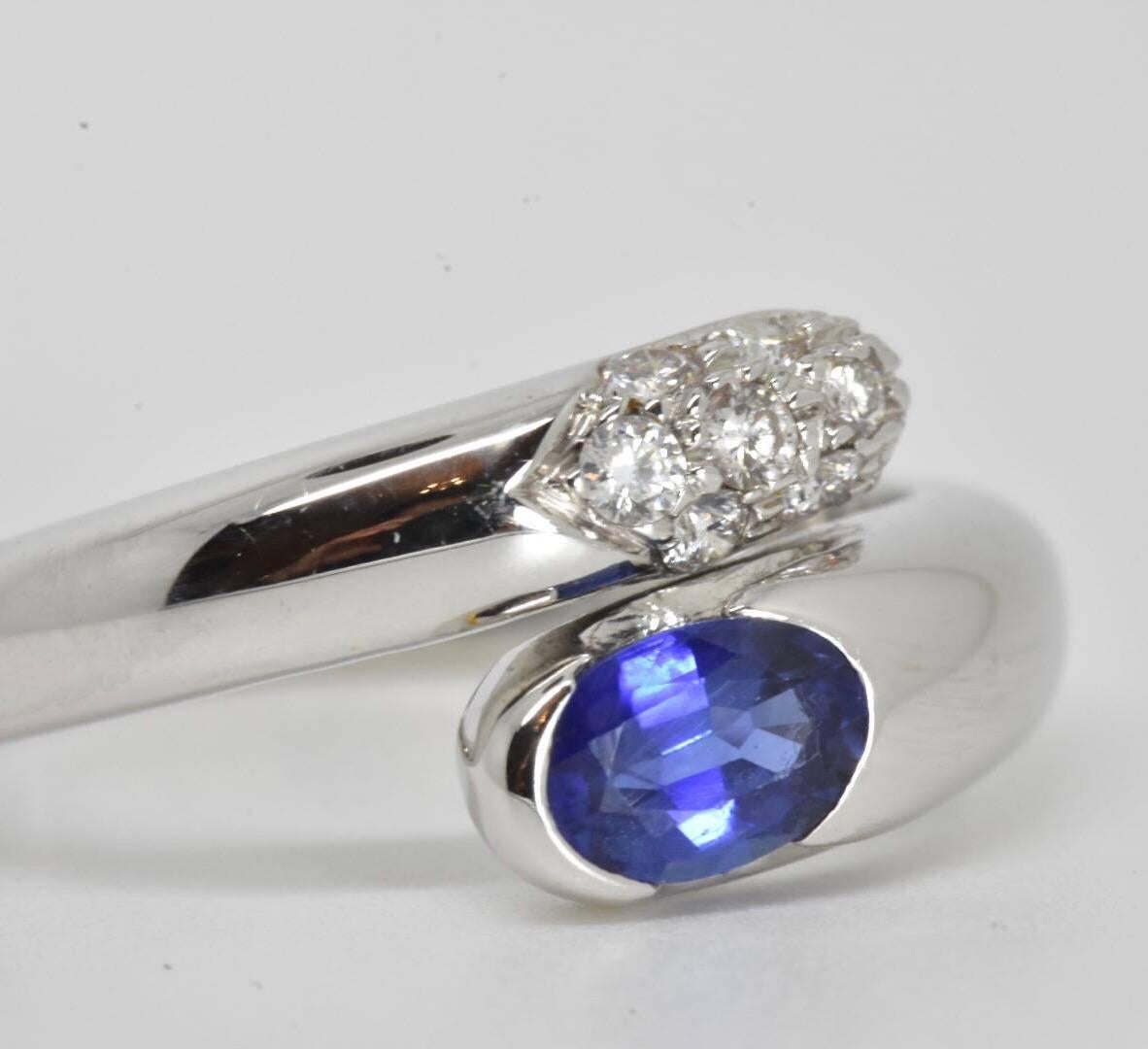 A Bvlgari sapphire and diamond bypass ring set in18k white gold. The ring features a wrap-around design set with an oval shaped natural sapphire of approx 0.65 carat of medium dark tone with 9 brilliant cut diamonds of approx 0.14 carat 
Ring size