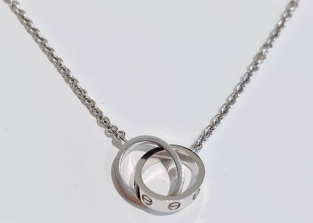 A Cartier necklace from the LOVE collection set in 18k white gold in a polished finish and has the double LOVE ring pendant. The rings are attached to a  rolo link chain of approx 44CM . 
Hallmarks-  Cartier CGK137 AU 750
The necklace is sold with