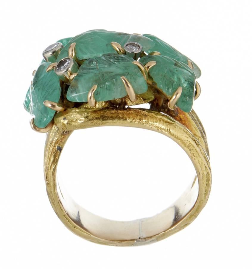 
An vintage emerald and diamond dress ring set in 18k yellow gold. The ring features a claw set with seven carved emerald leaves with four brilliant and old cut diamond accents, on a bark textured triple shank which is unmarked 
Size: M
Weight: 21.2