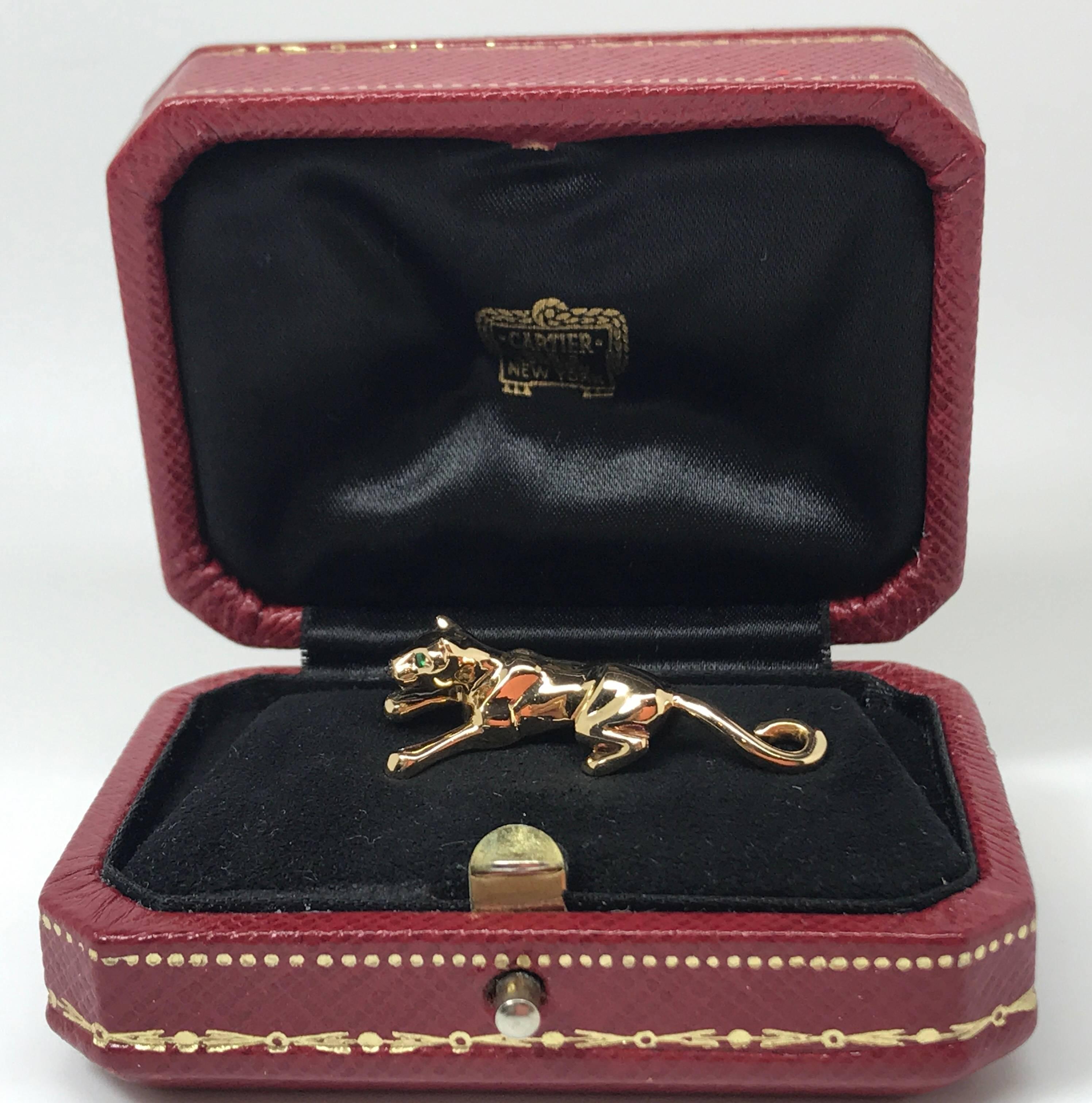 A Cartier gem-set panther pin brooch set in 18k yellow gold. The brooch features a stylised panther, with onyx nose and green garnet eyes. Signed and numbered Cartier, 615603. French assay marks, sold with the original Cartier case.
Length: