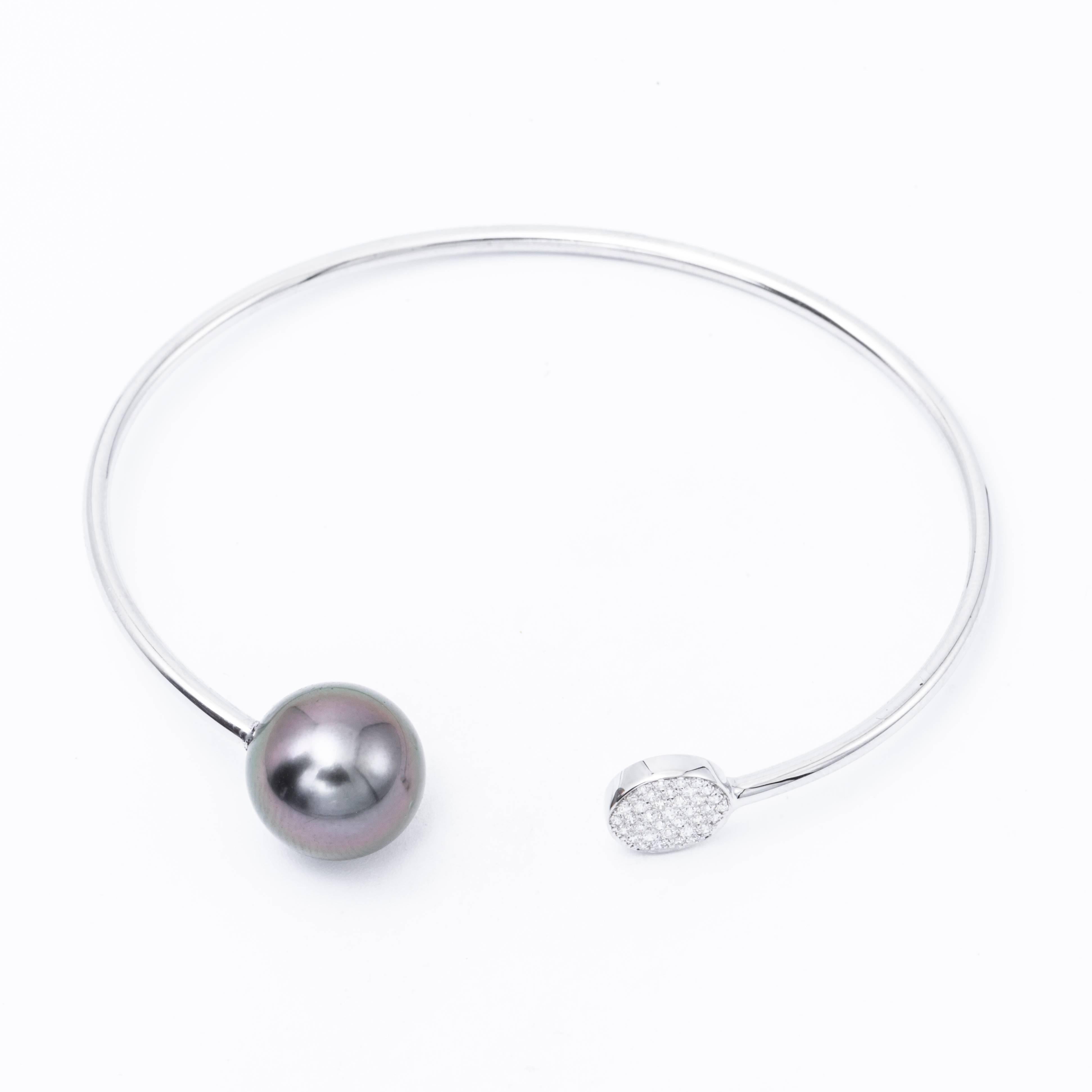 18 Karat white gold bangle bracelet featuring 32 round brilliants weighing 0.12 carats and one grey Tahitian Cultured Pearl measuring 11-12 mm.
Color G-H
Clarity SI